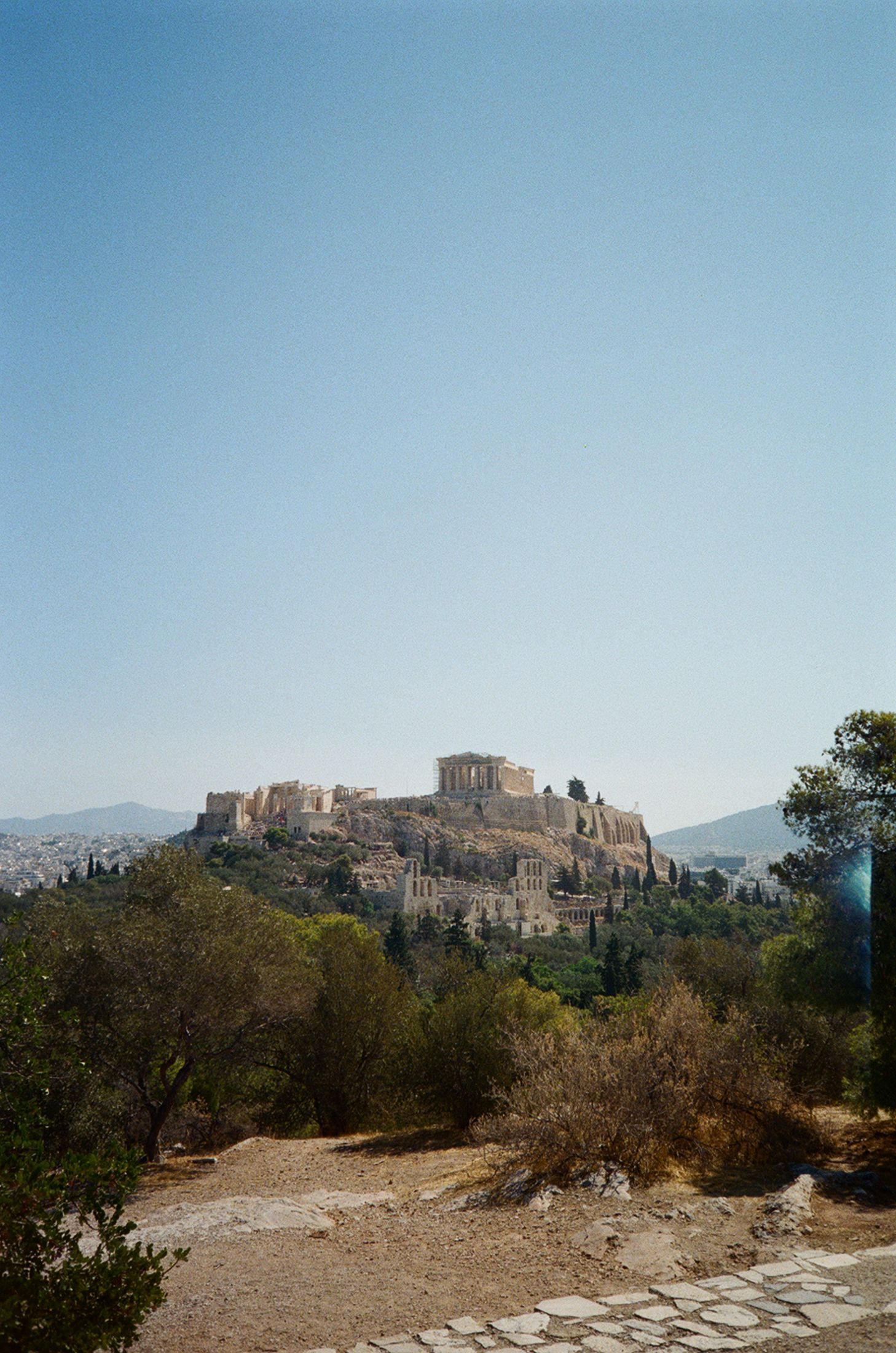 Ancient Acropolis ruins perched atop a hill in Athens against blue sky viewed from multiple angles in panoramic shots.
