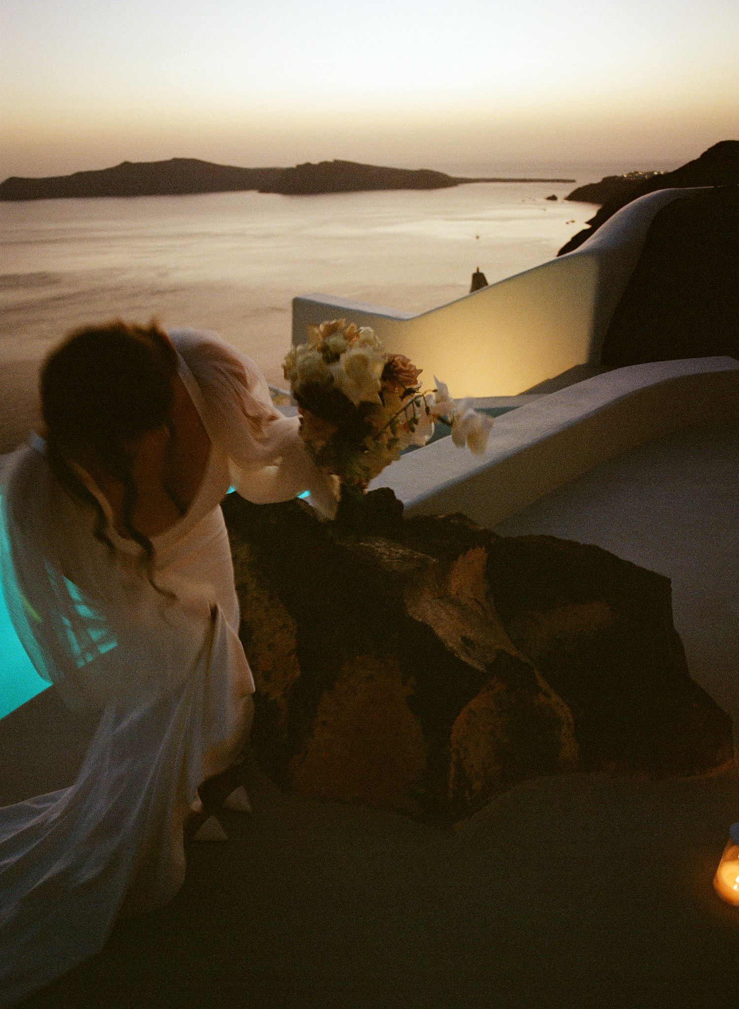 A romantic sunset silhouette of a couple embracing against a golden sky overlooking a coastal landscape.