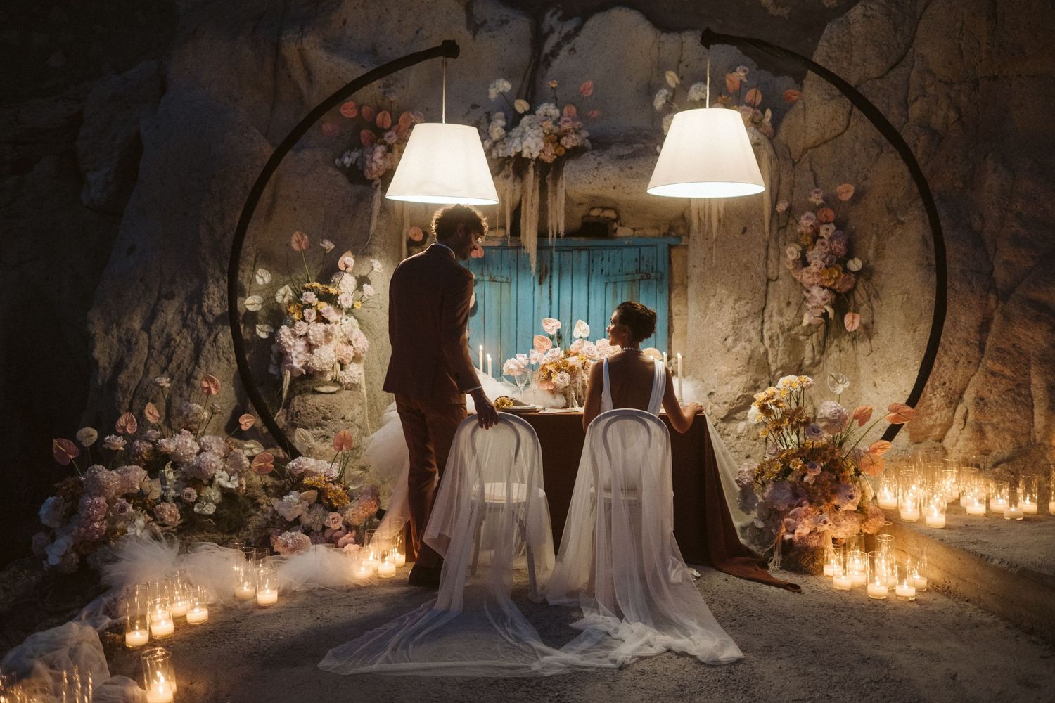 A romantic couple at an elegantly decorated wedding altar with white flowers, archway, and glowing candlelight.