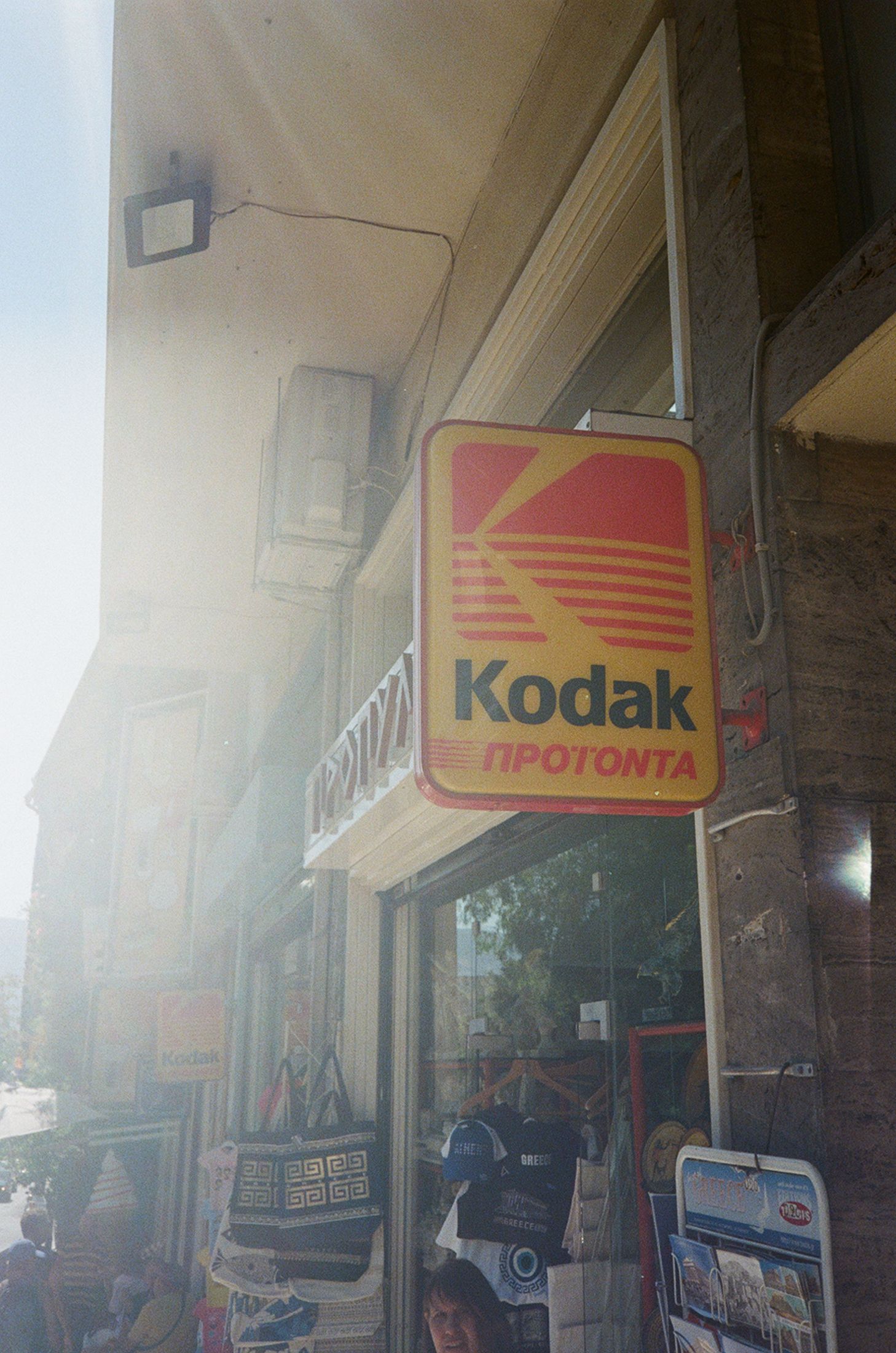 Vintage storefront signs showing Kodak and Fototinta logos on a building exterior in faded lighting conditions.