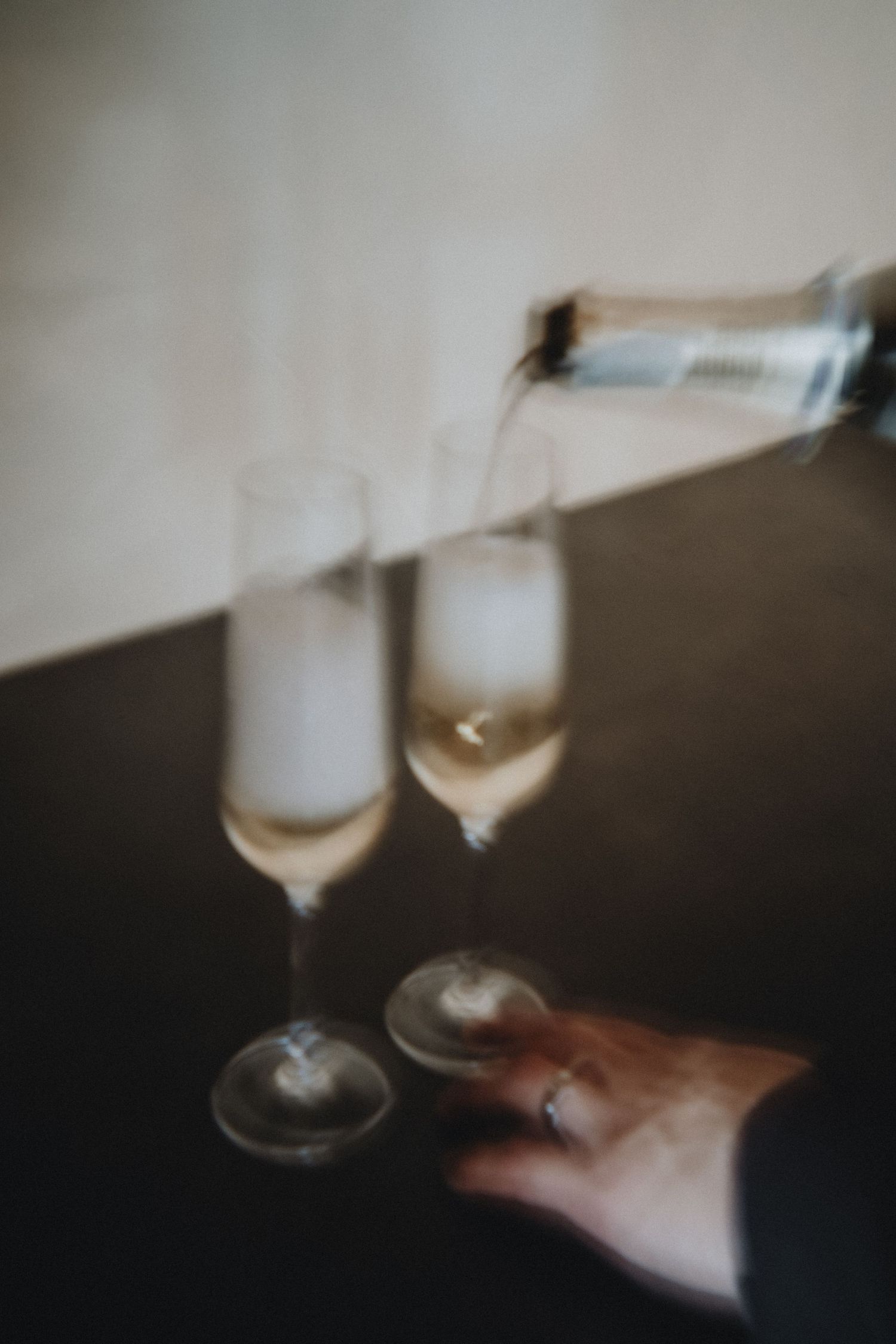 A series of blurred artistic photographs showing wine glasses held against a dark background with moody lighting.