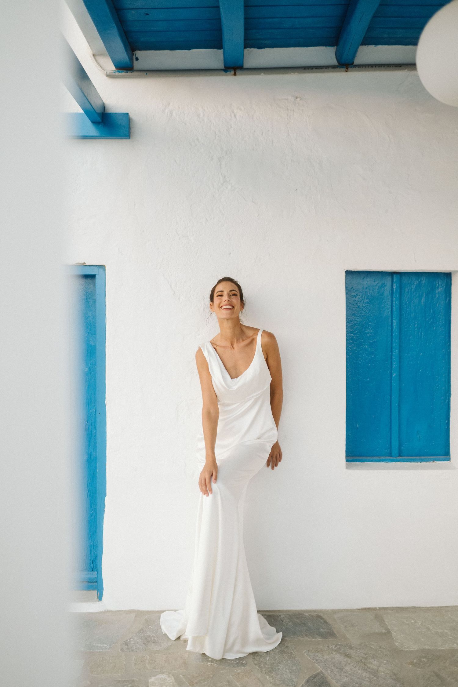Modern architectural details blend bright blue accents with white walls, framing someone in an elegant flowing white gown.