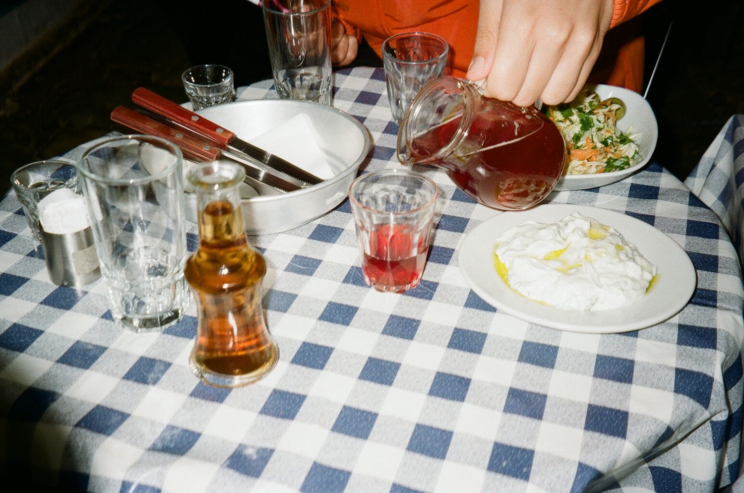 A table set with blue and white checkered tablecloth shows various plates and glasses during a meal service.