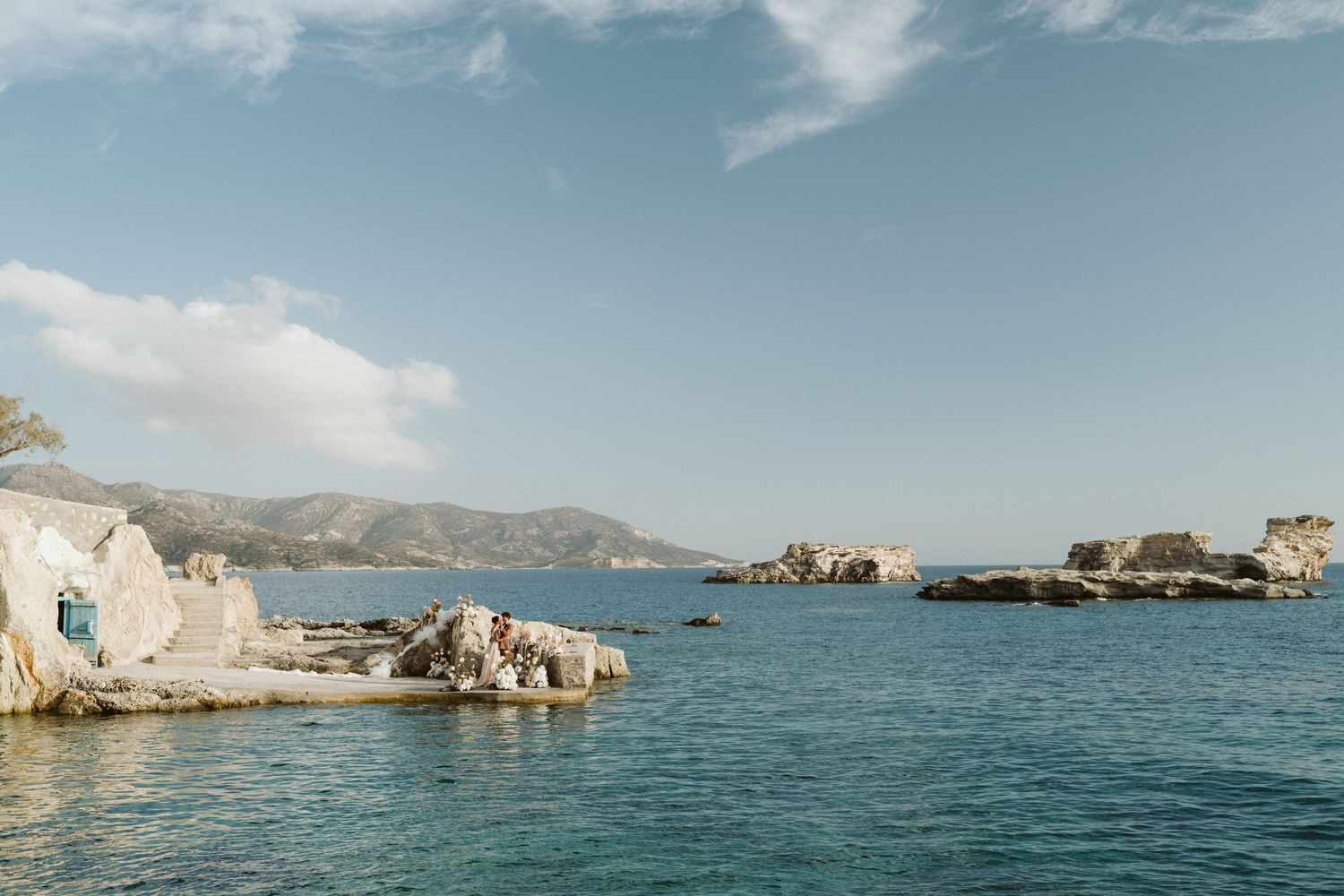 Rocky coastal landscape with white limestone formations and turquoise Mediterranean waters under a bright blue sky.