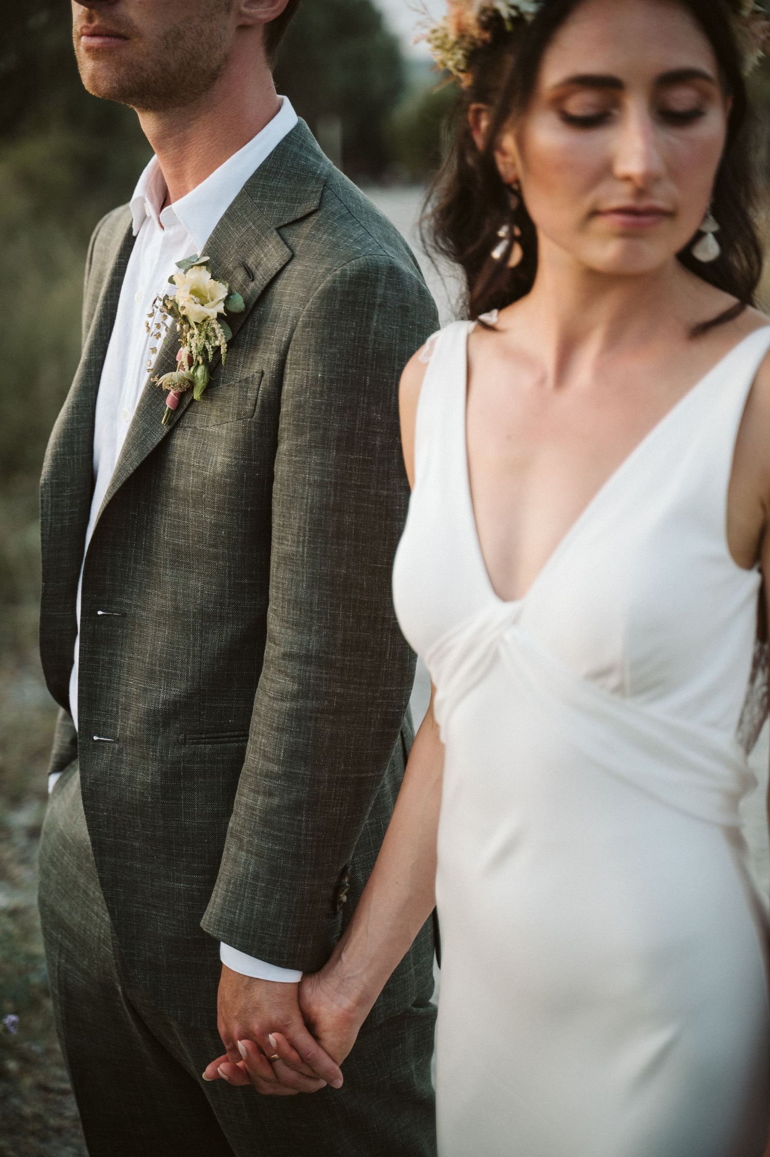 Stylish bride and groom holding hands in elegant wedding attire.