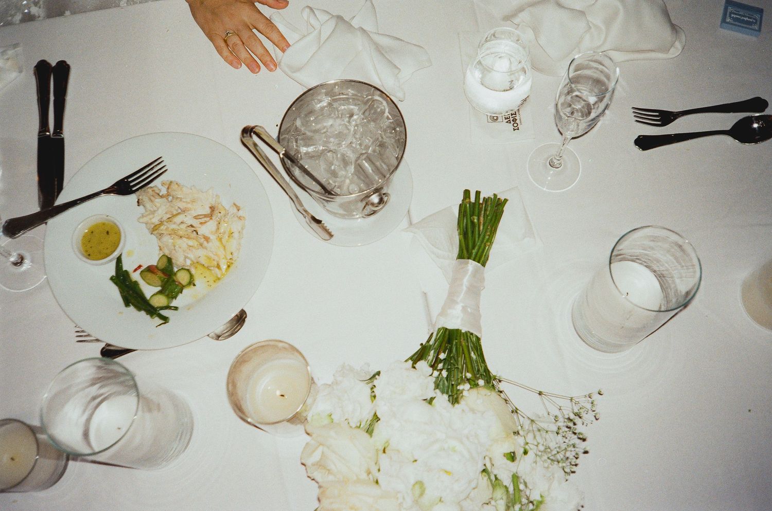 Overhead view of a formal dining table with elegant place settings, white floral arrangements, and glassware.