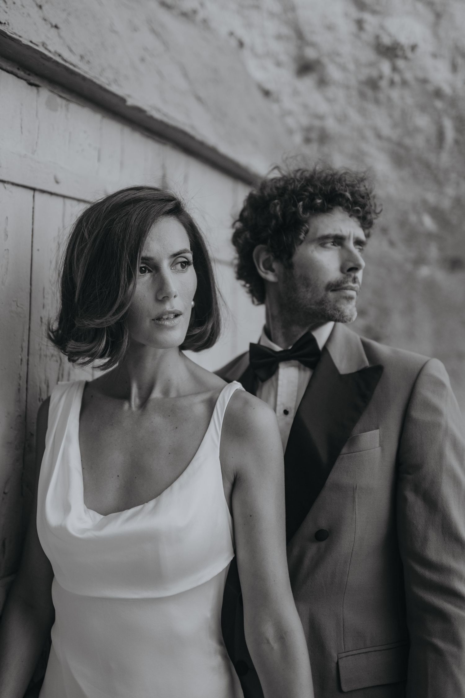 Black and white portrait of couple in formal attire with woman in white dress and man in dark suit and bowtie.
