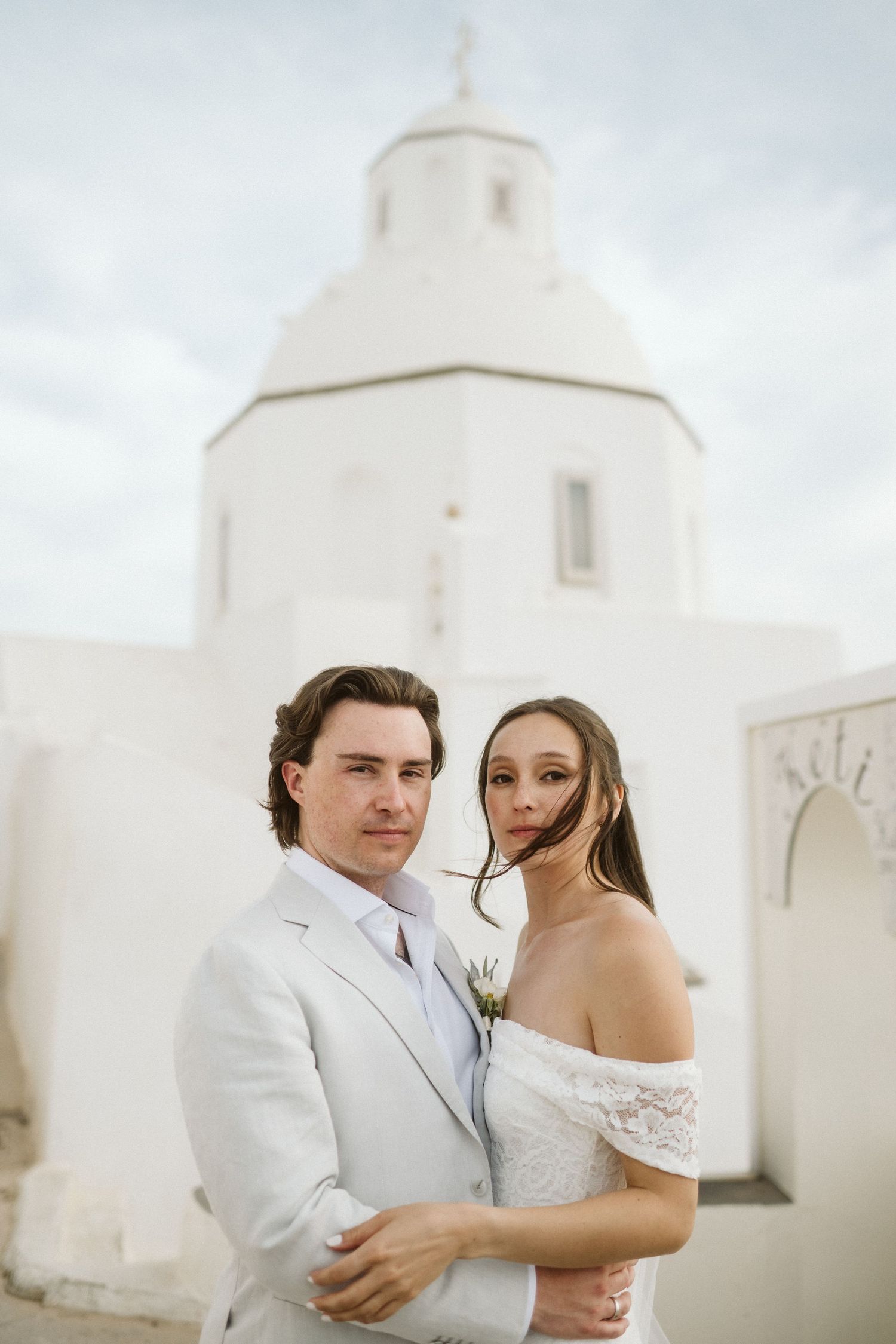 Wedding photo in front of a white Mediterranean church dome.