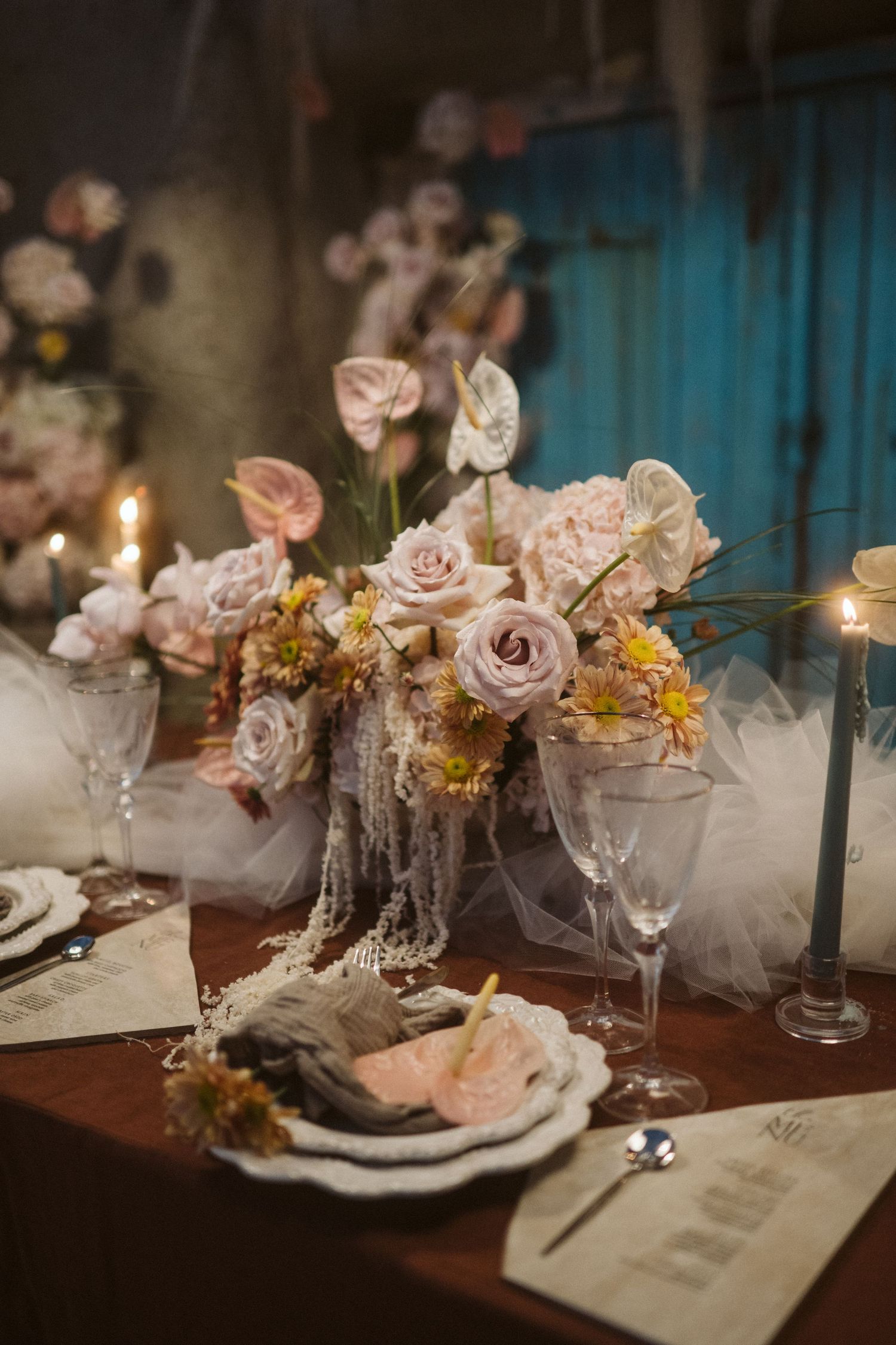 Romantic table setting with pale pink roses, candles and crystal glasses for an elegant evening dinner party.