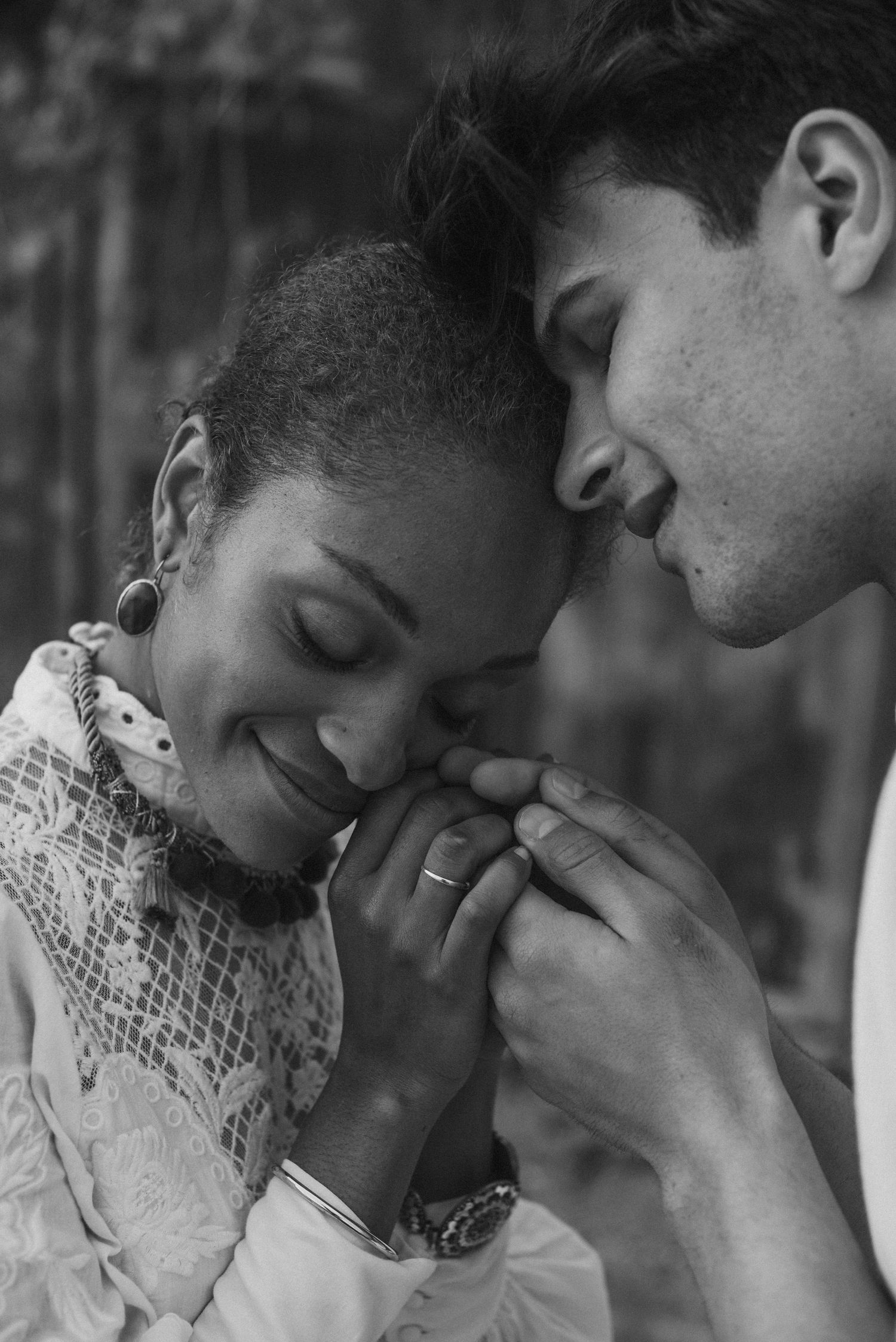 An intimate black and white portrait captures a tender moment between two people.