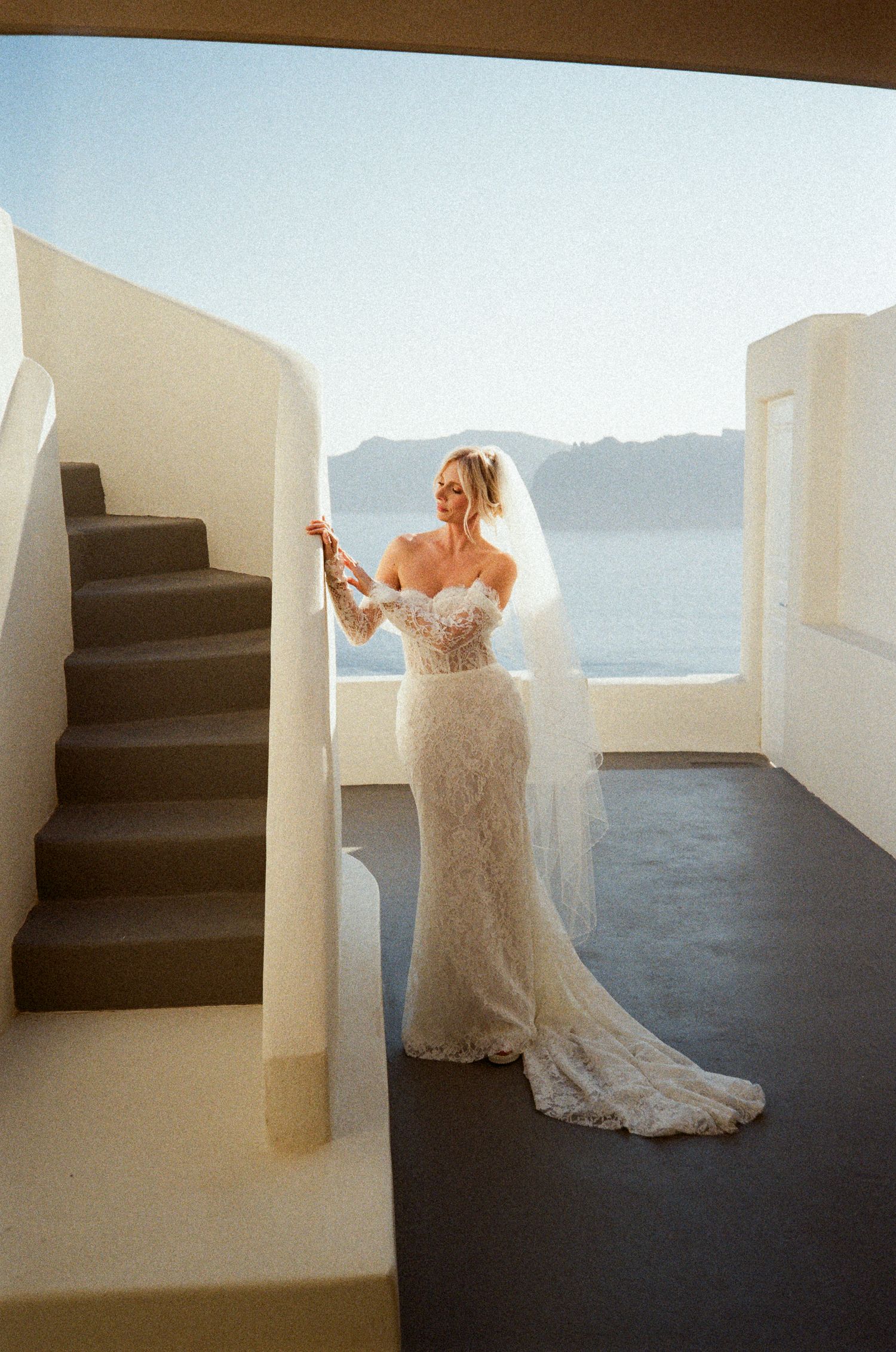 A series of wedding photos showing a bride in a lace dress twirling against white Mediterranean architecture and ocean views.