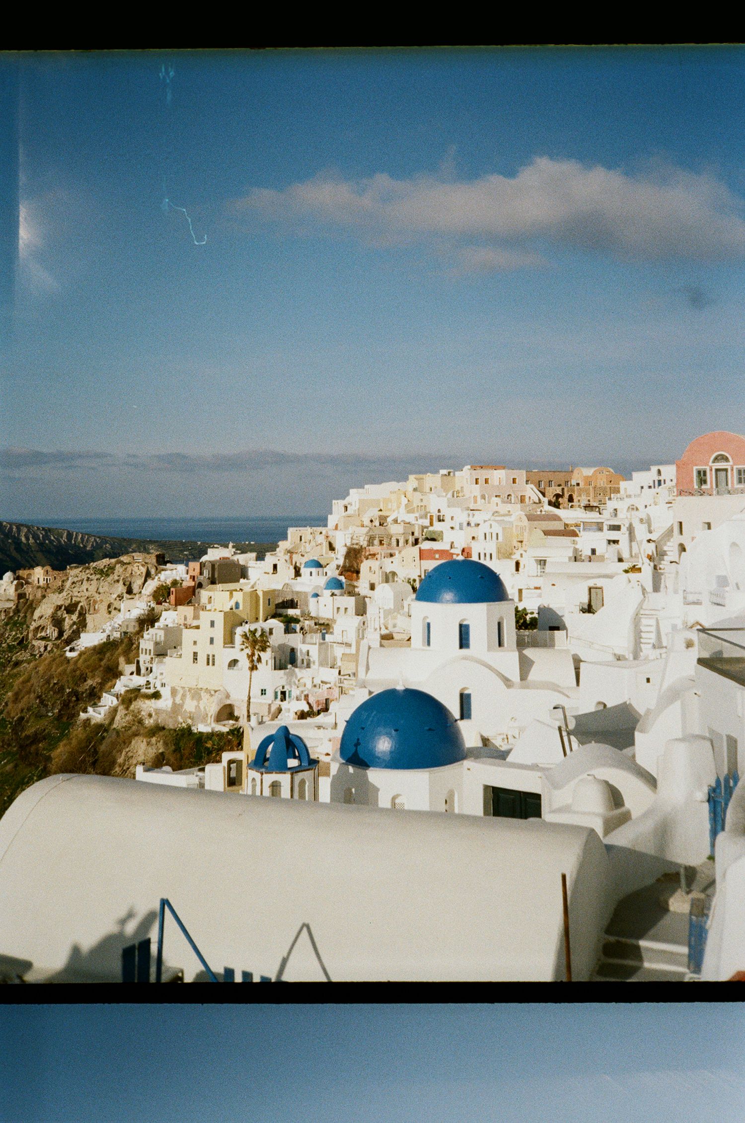A panoramic view of Santorini's iconic white buildings and blue domed churches against the Mediterranean sky.