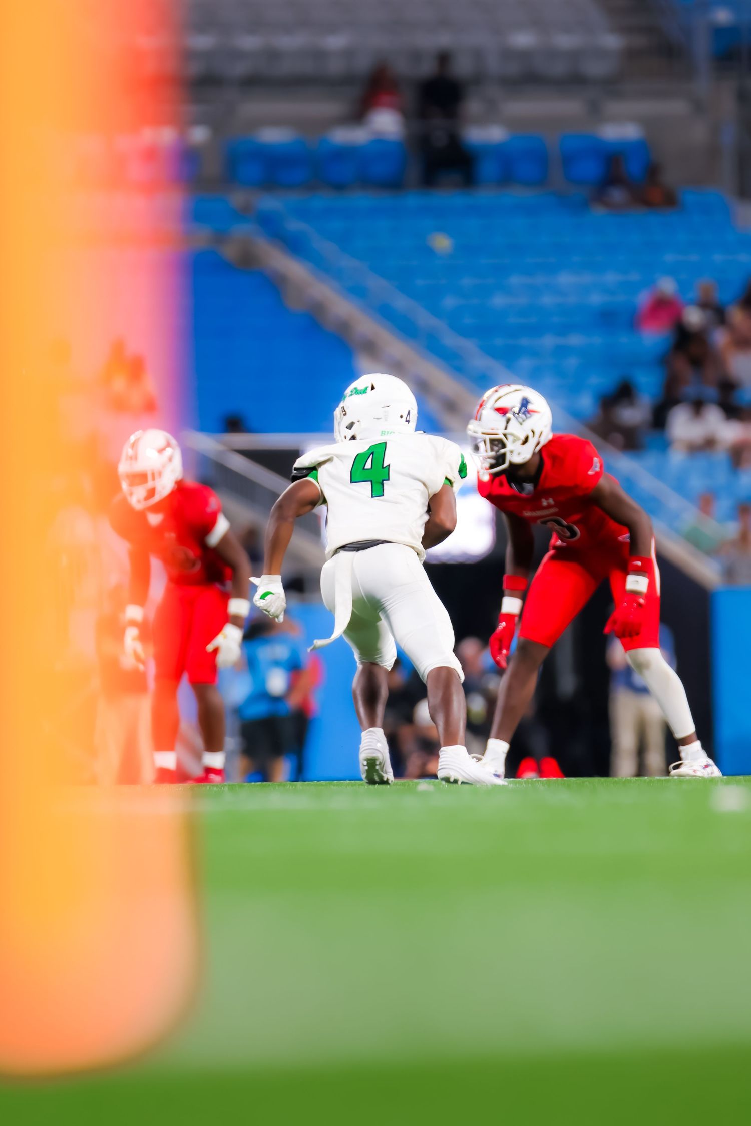 Football players in white and red uniforms compete on a professional stadium field during a college football game.