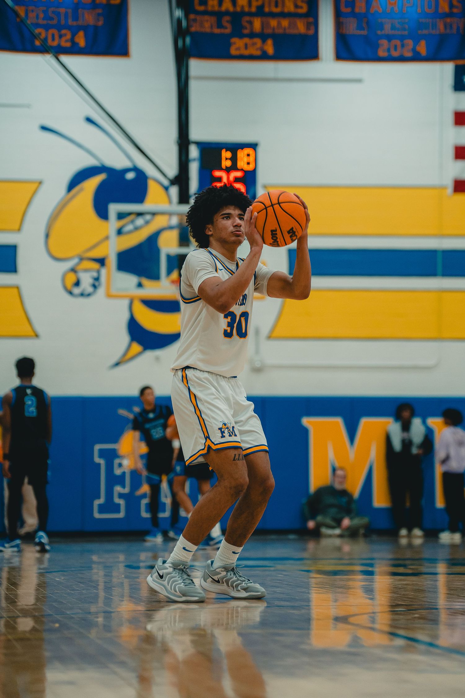 Basketball player #30 in white uniform prepares to shoot during indoor high school game.