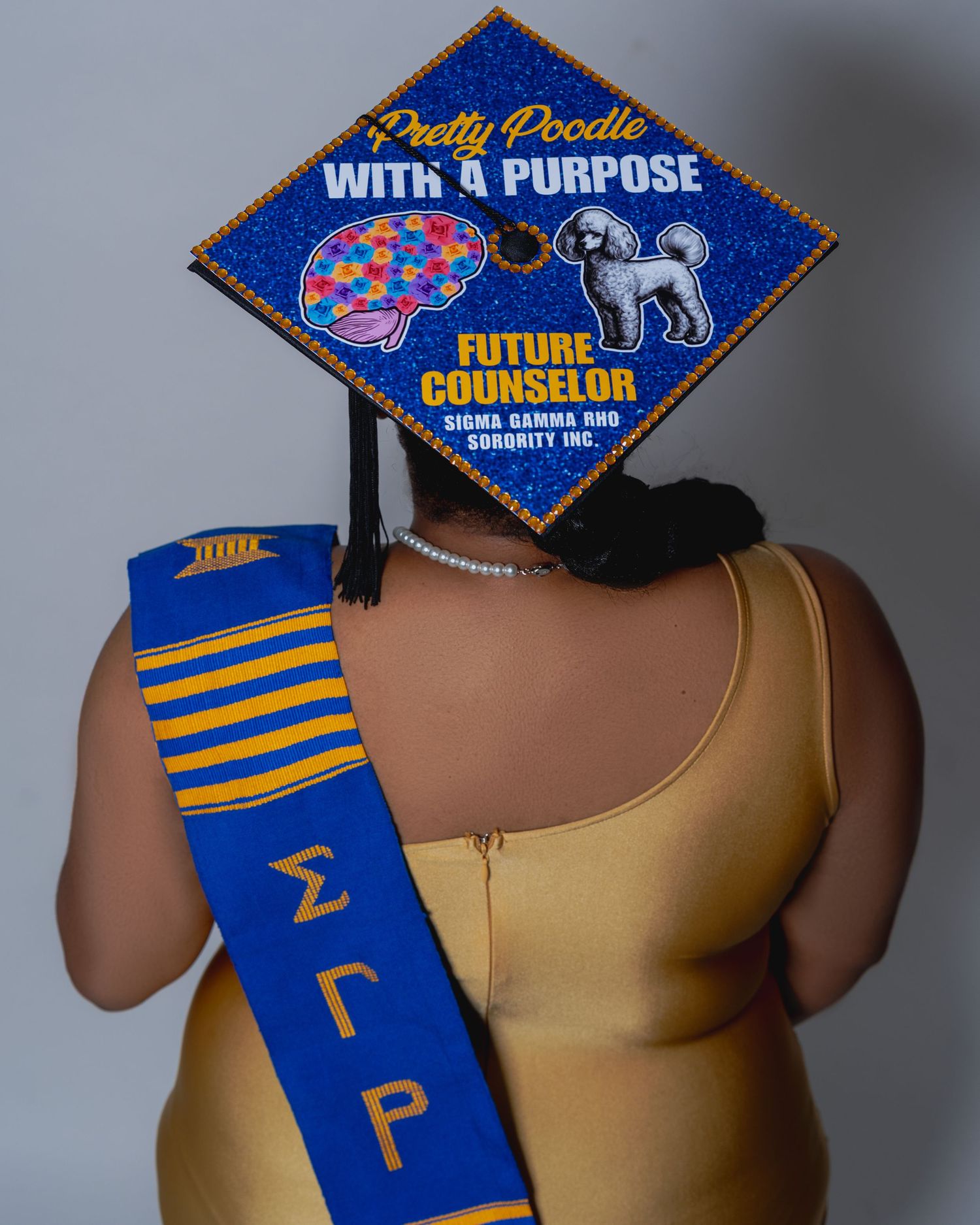 Graduation cap decorated with Pretty Poodle With A Purpose Future Counselor Sigma Gamma Rho sorority design.