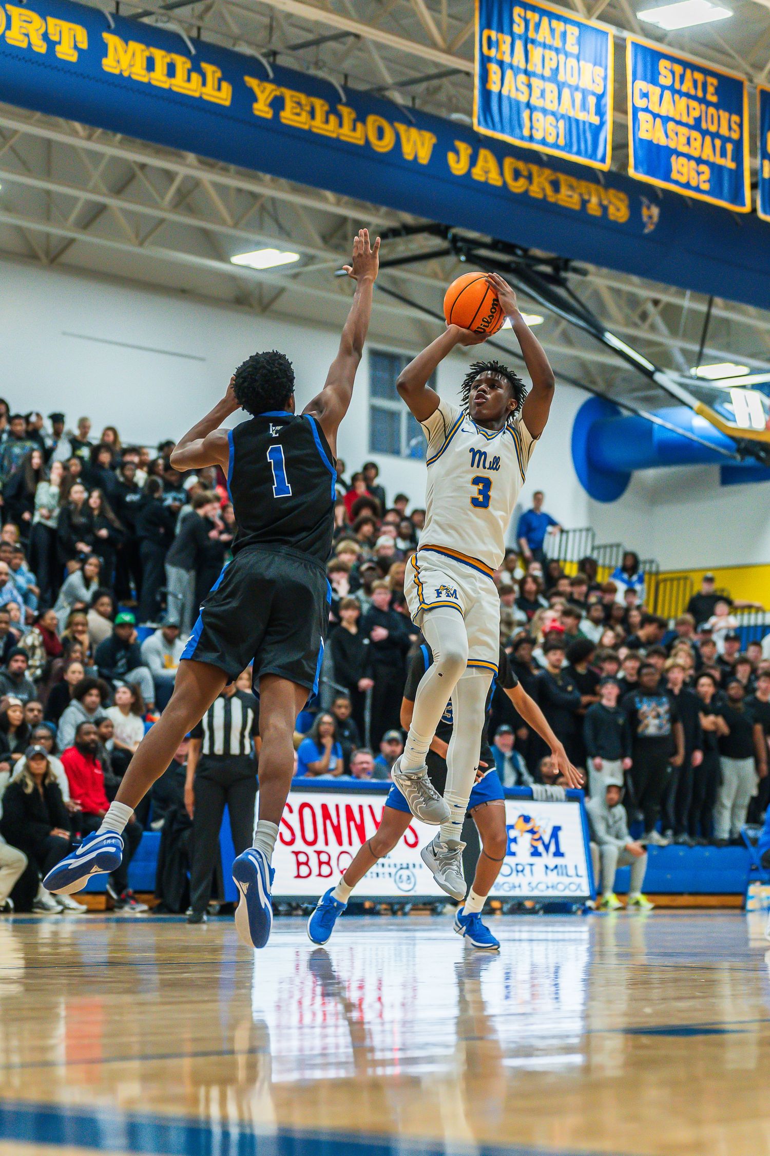 Basketball player #3 hits jump shot over defender during packed Port Mill Yellow Jackets game.