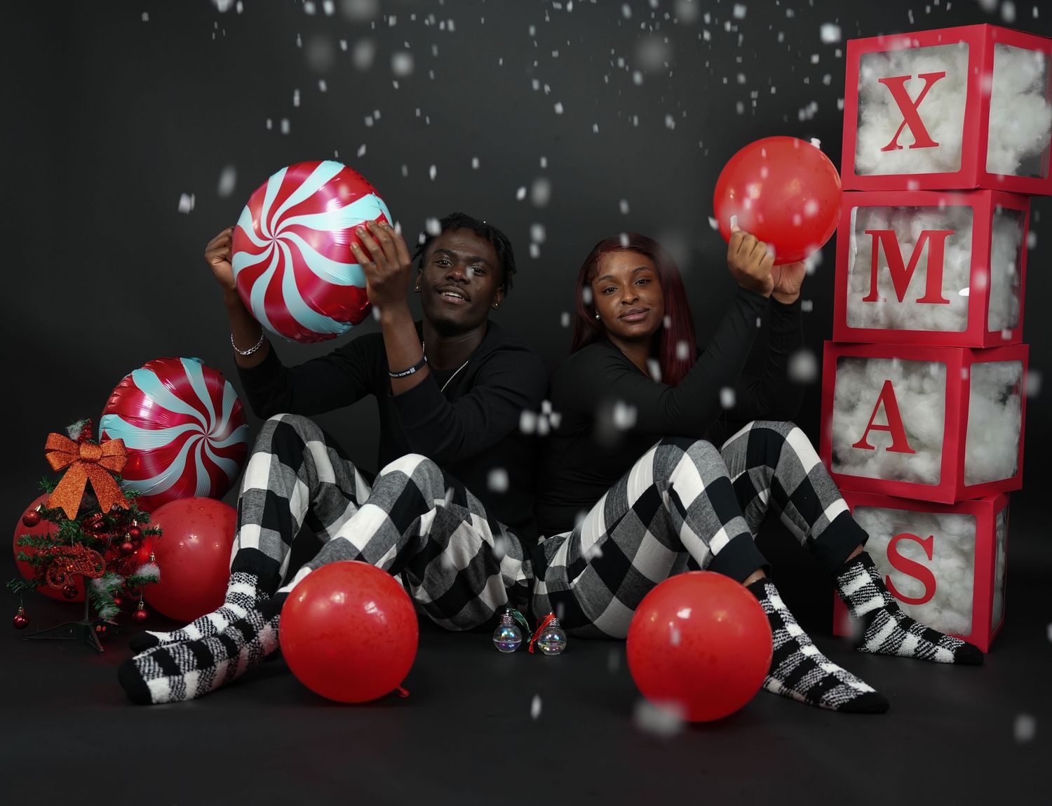 Couple sitting on floor with candy cane balloons and XMAS blocks in a Christmas photo session.