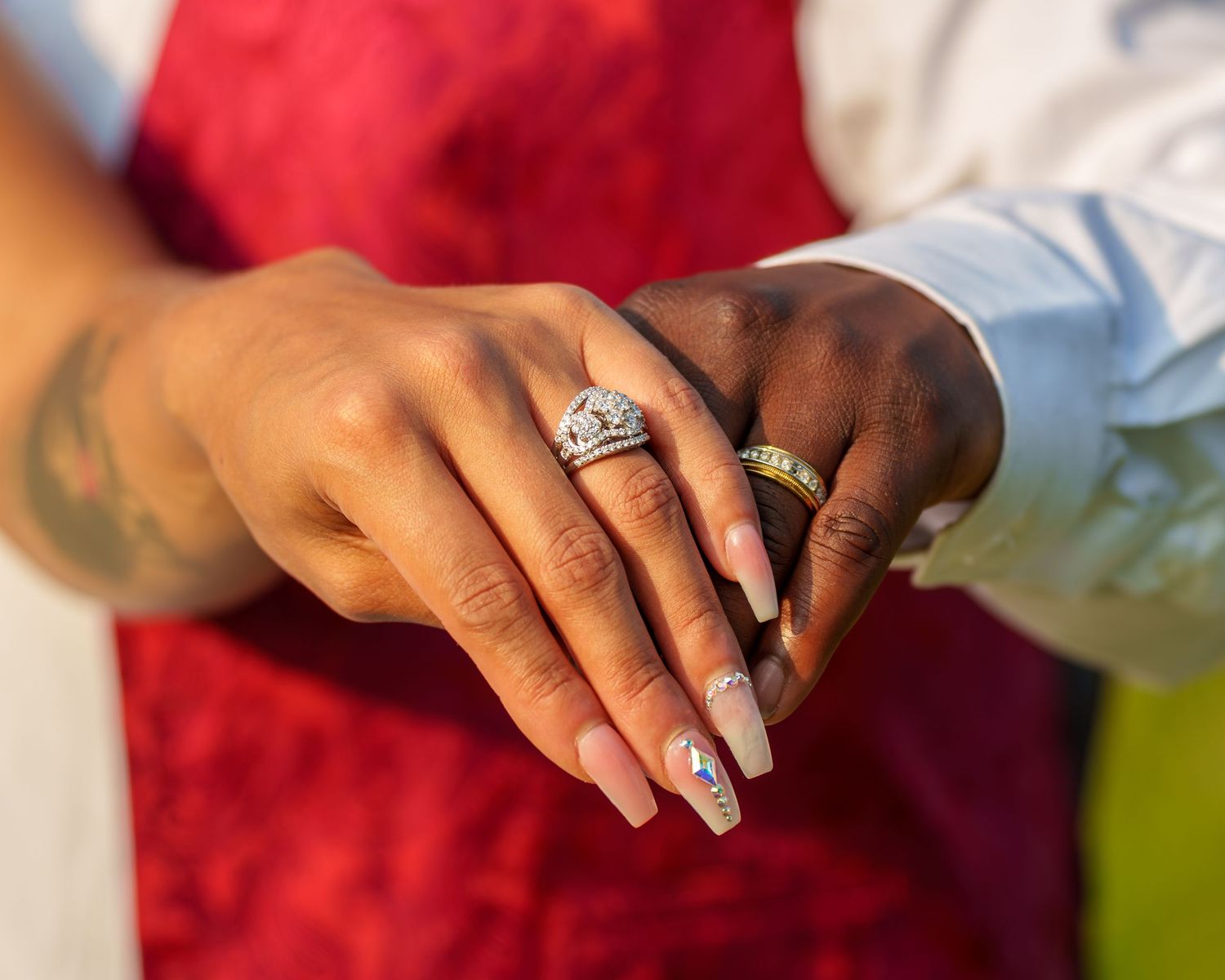 Close-up of newlyweds hands showing diamond wedding rings with colorful nail art details.