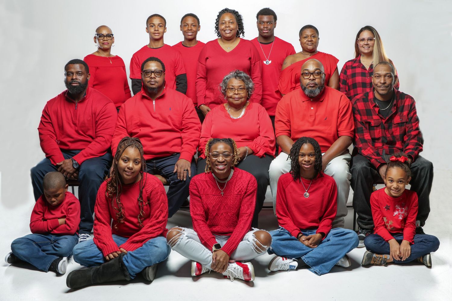 Multi-generational family photo with everyone dressed in red clothing in a professional studio setting.