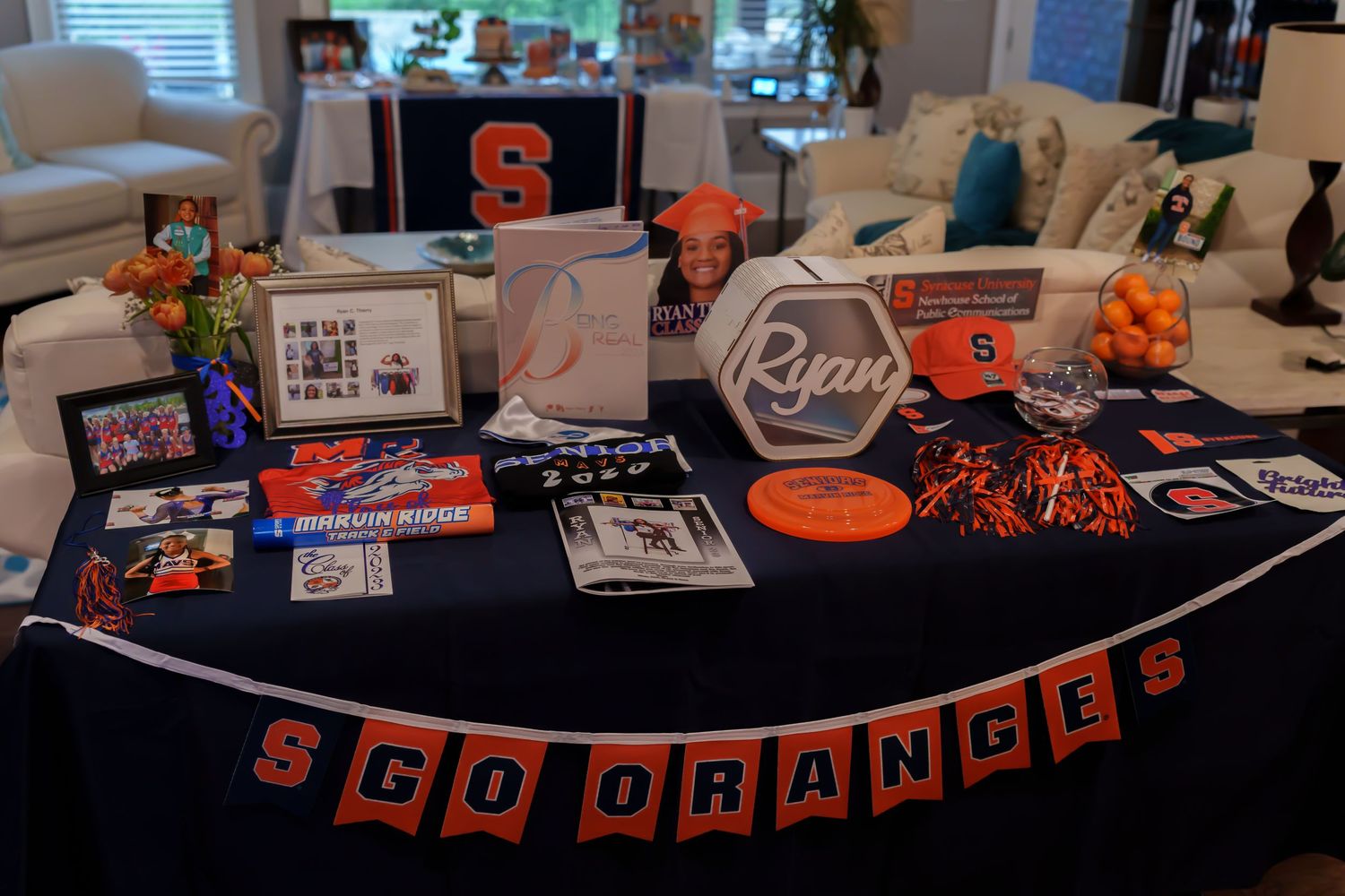 Syracuse University graduation party table display with SCO Oranges banner, photos, and orange decorations.