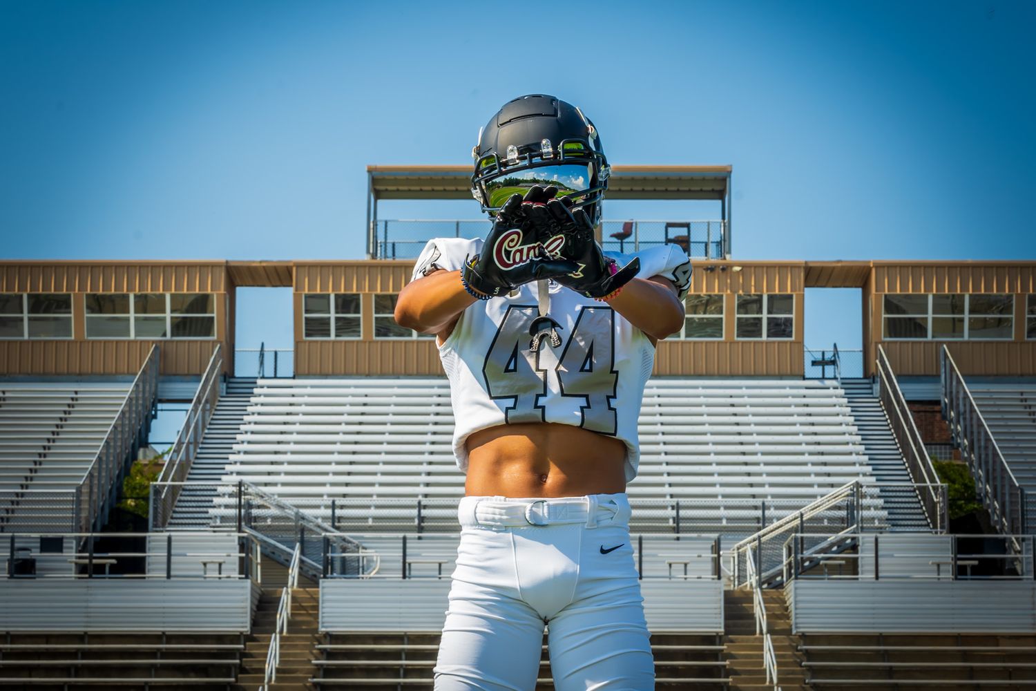 Football player wearing number 44 white uniform standing with back to camera at stadium.