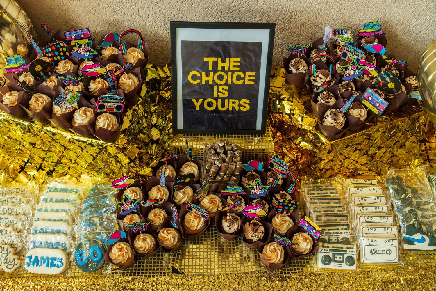 Gold dessert table with cupcakes, cookies, and candy featuring a 'The Choice Is Yours' framed sign at a birthday party.