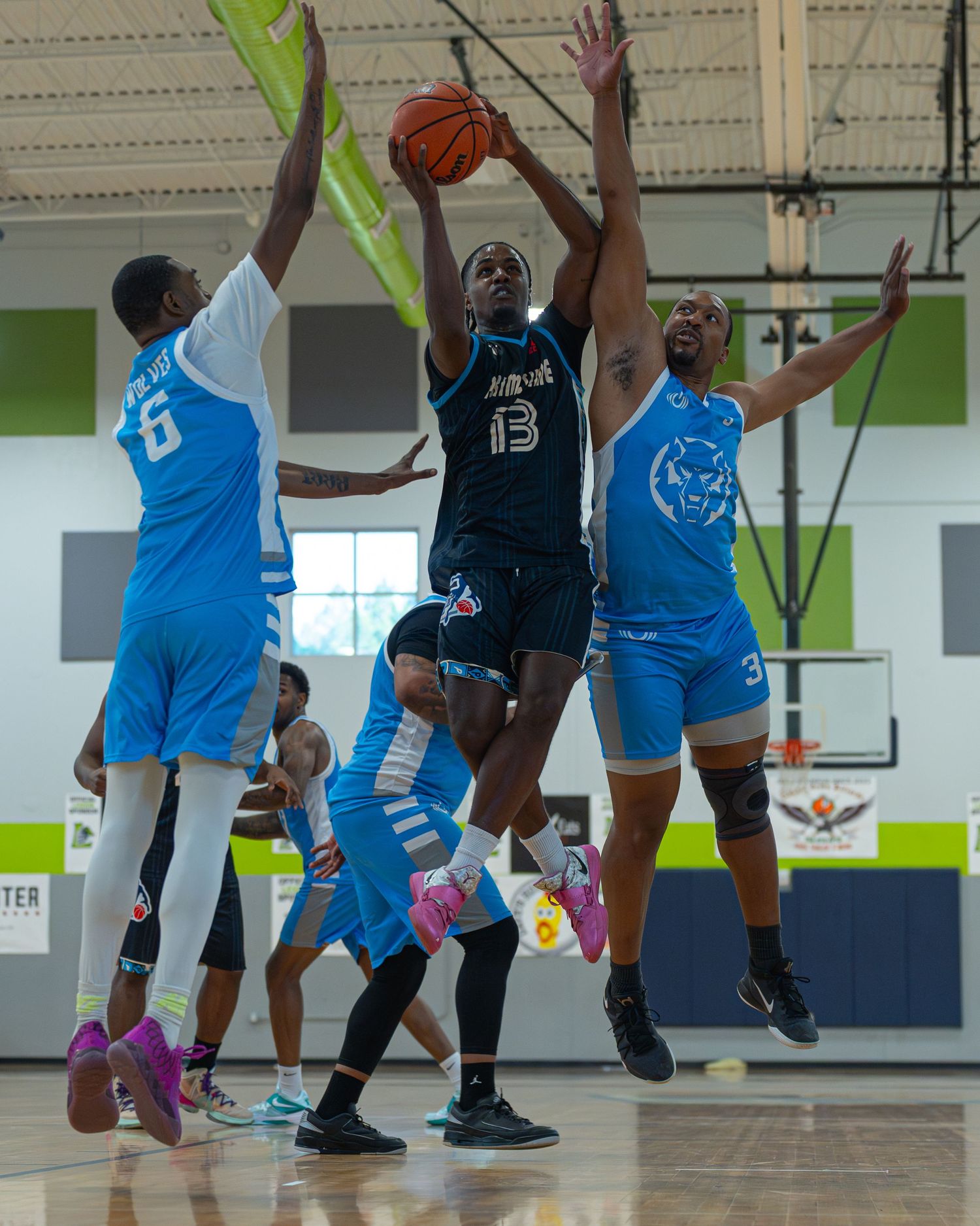 Basketball player number 13 driving to the basket during an indoor league game.