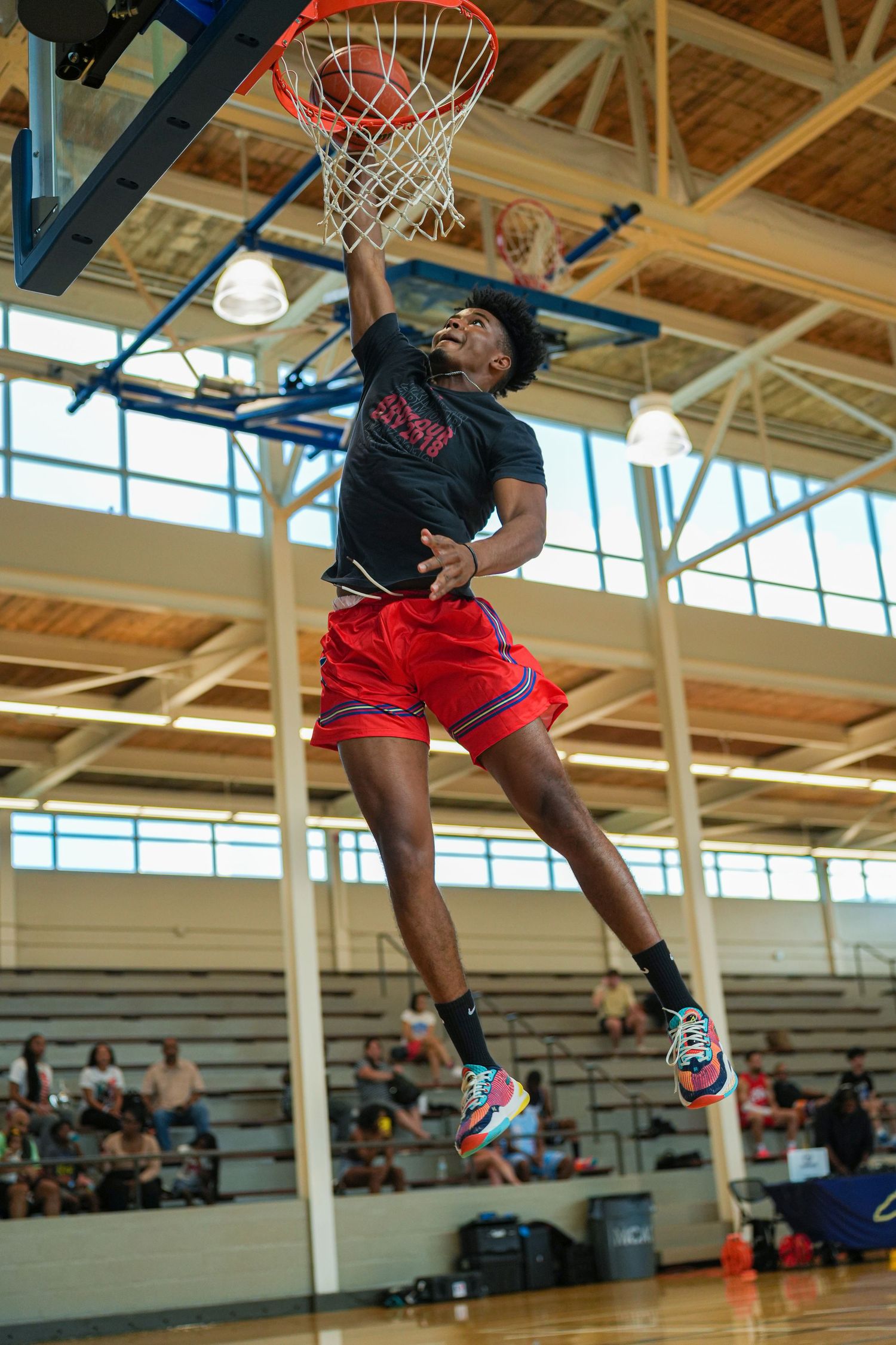 Athletic basketball player executes powerful slam dunk during indoor recreational league game.