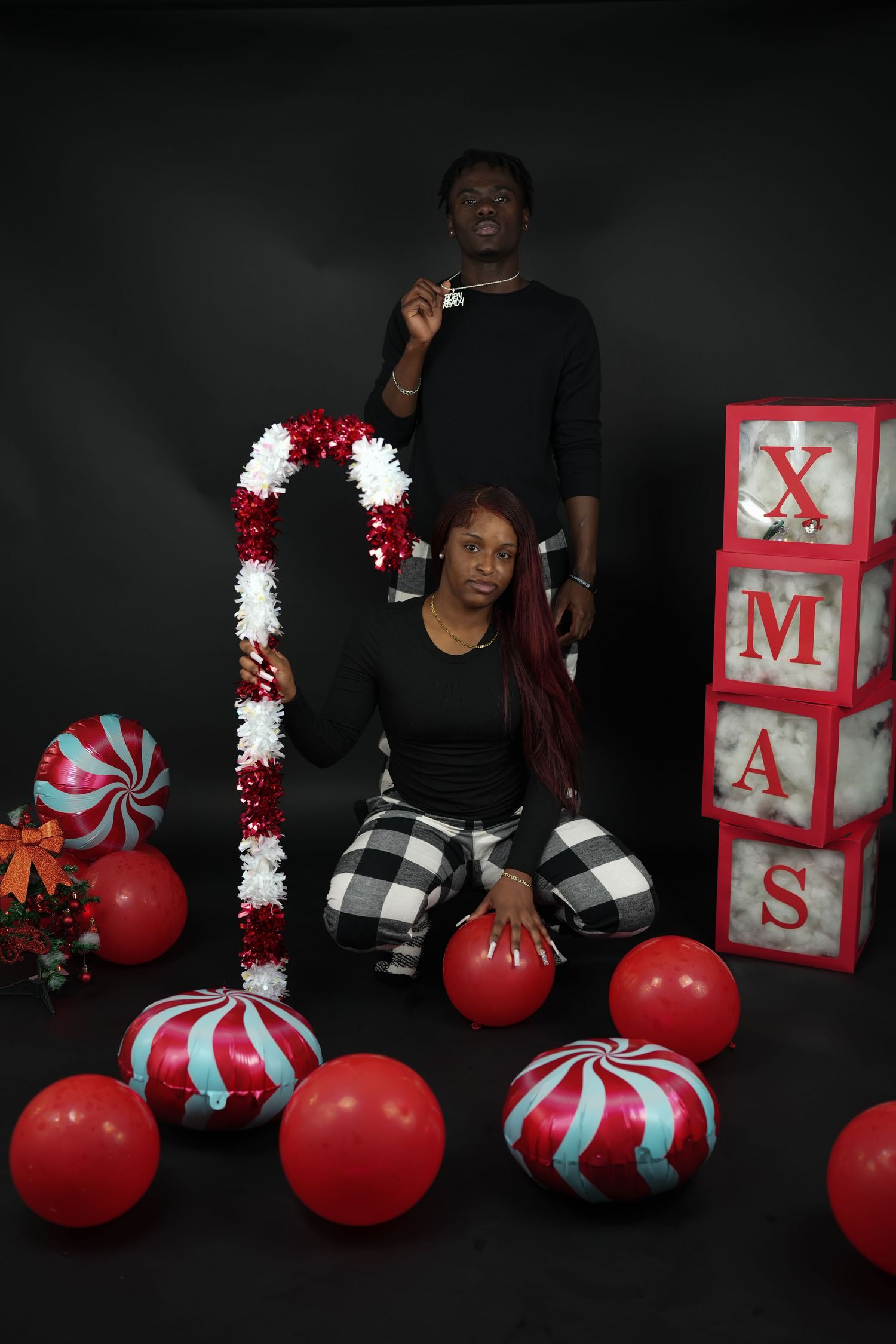 Couple posing with a large candy cane prop and XMAS blocks in a festive Christmas studio shoot.