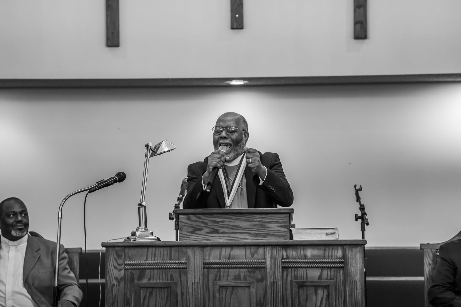 A black and white photo of a man wearing a medal speaking at a church pulpit.