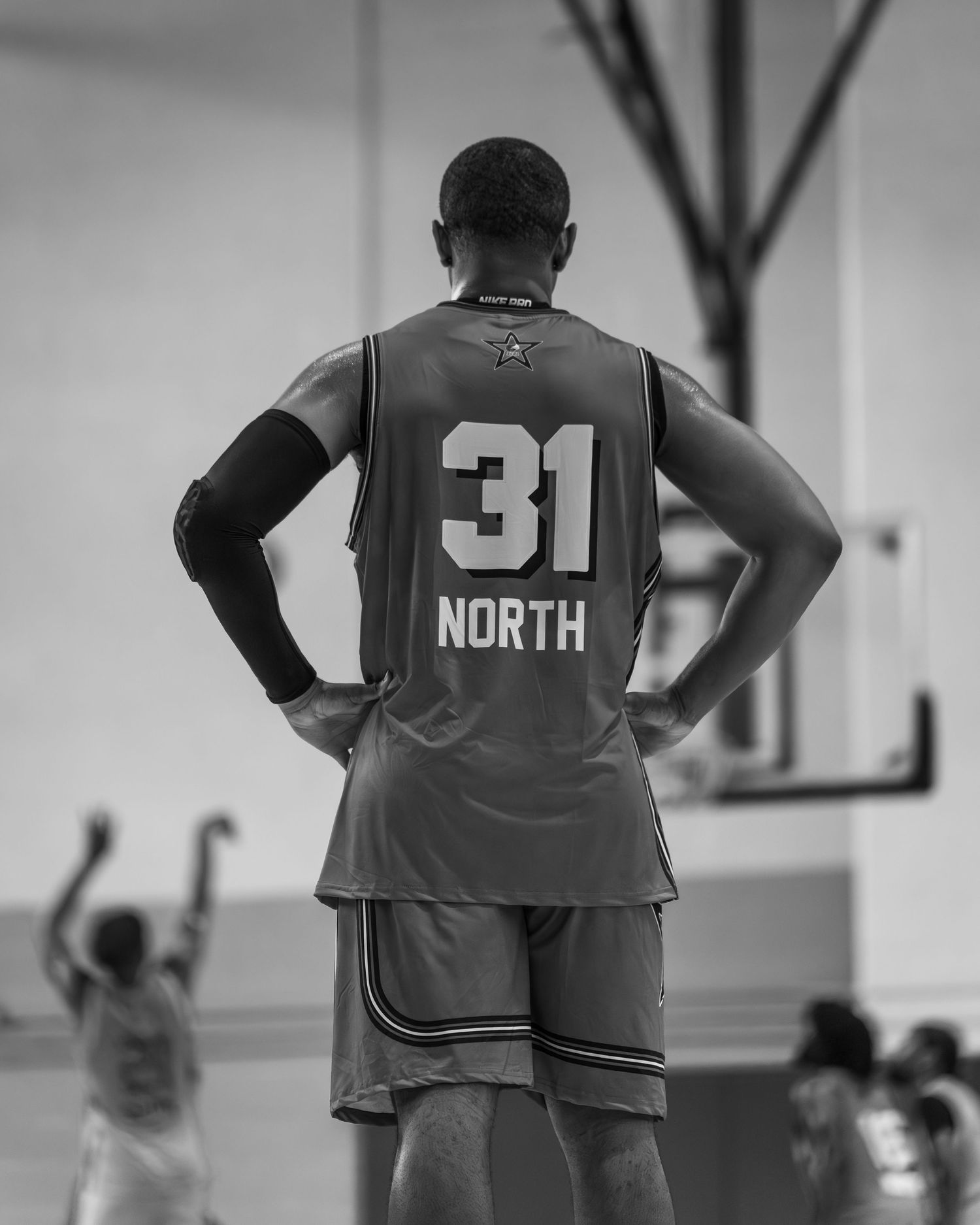 Black and white rear view of basketball player #31 North standing on indoor court.