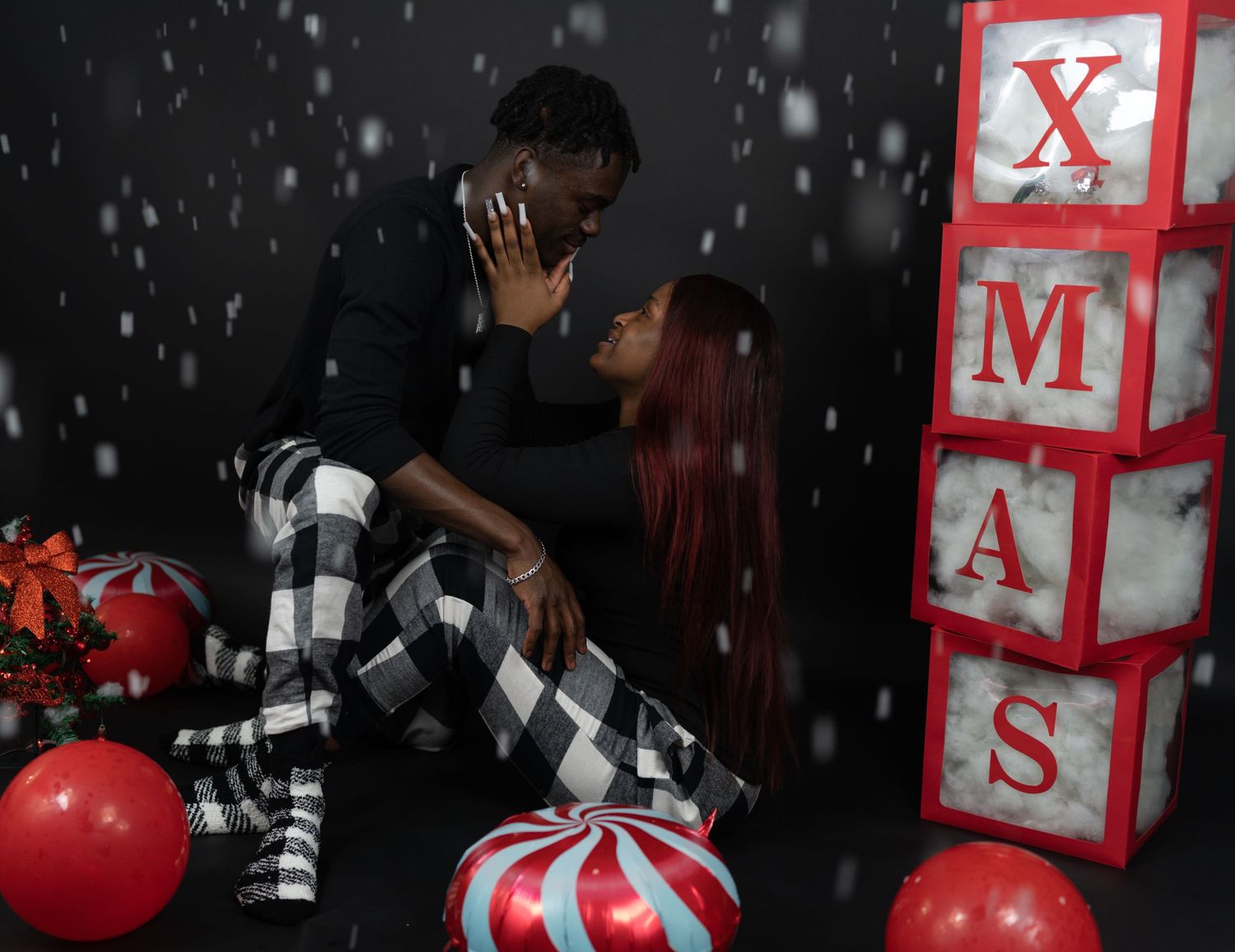 Couple sharing romantic moment during Christmas photo shoot with festive decorations.