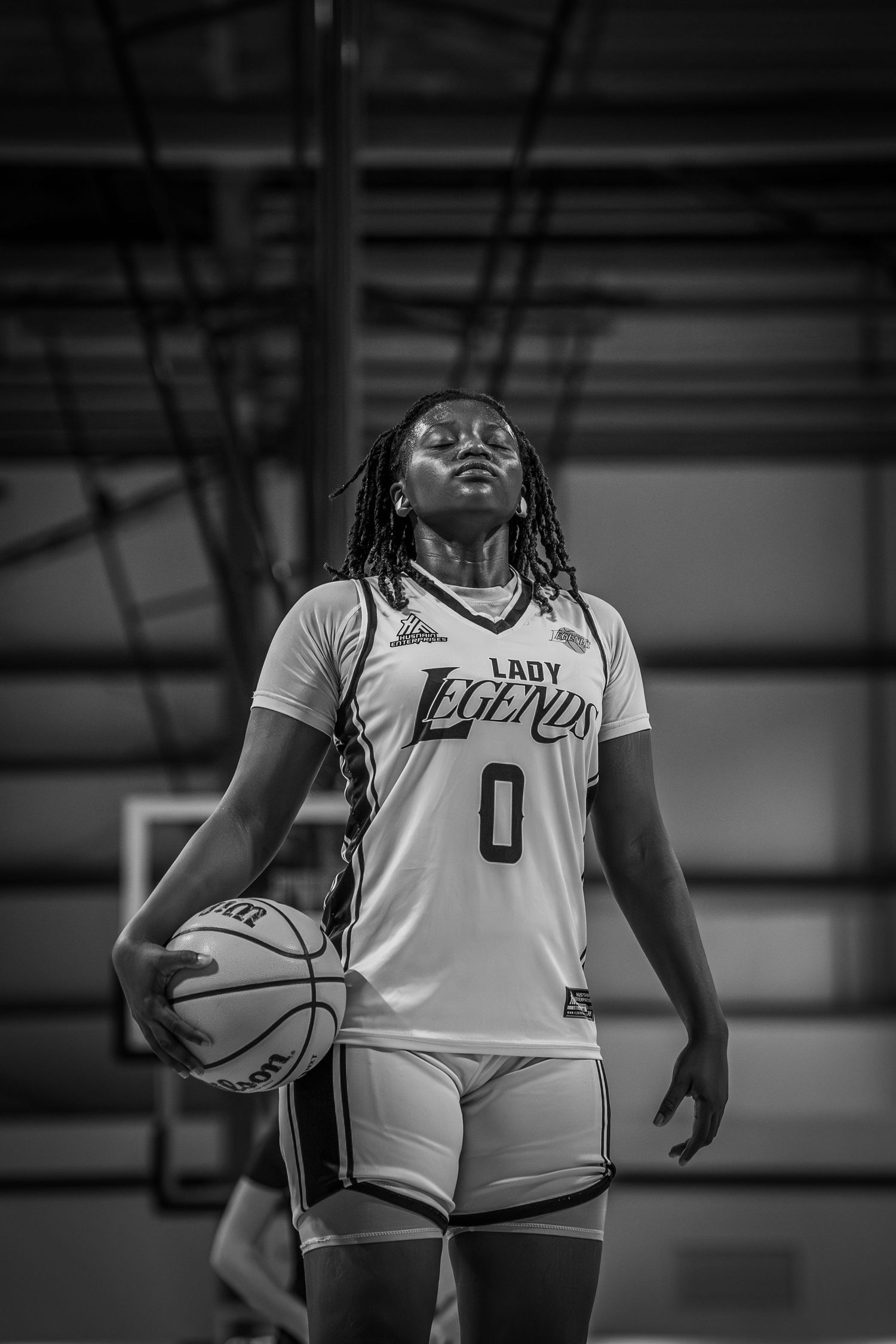 Black and white portrait of Lady Legends #0 female basketball player holding ball indoors.