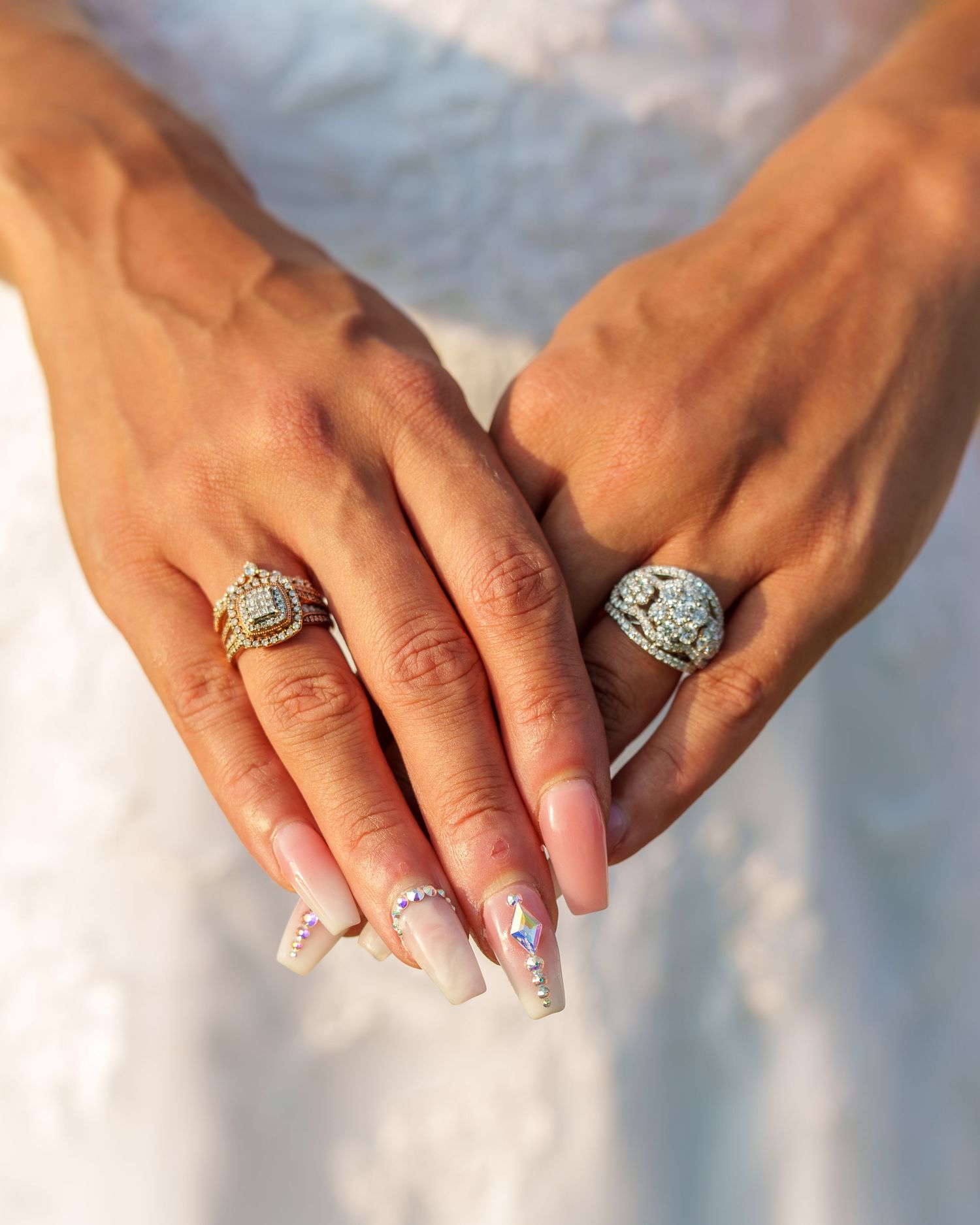 Close-up of bride's hands showing two ornate diamond wedding rings with decorative acrylic nails.