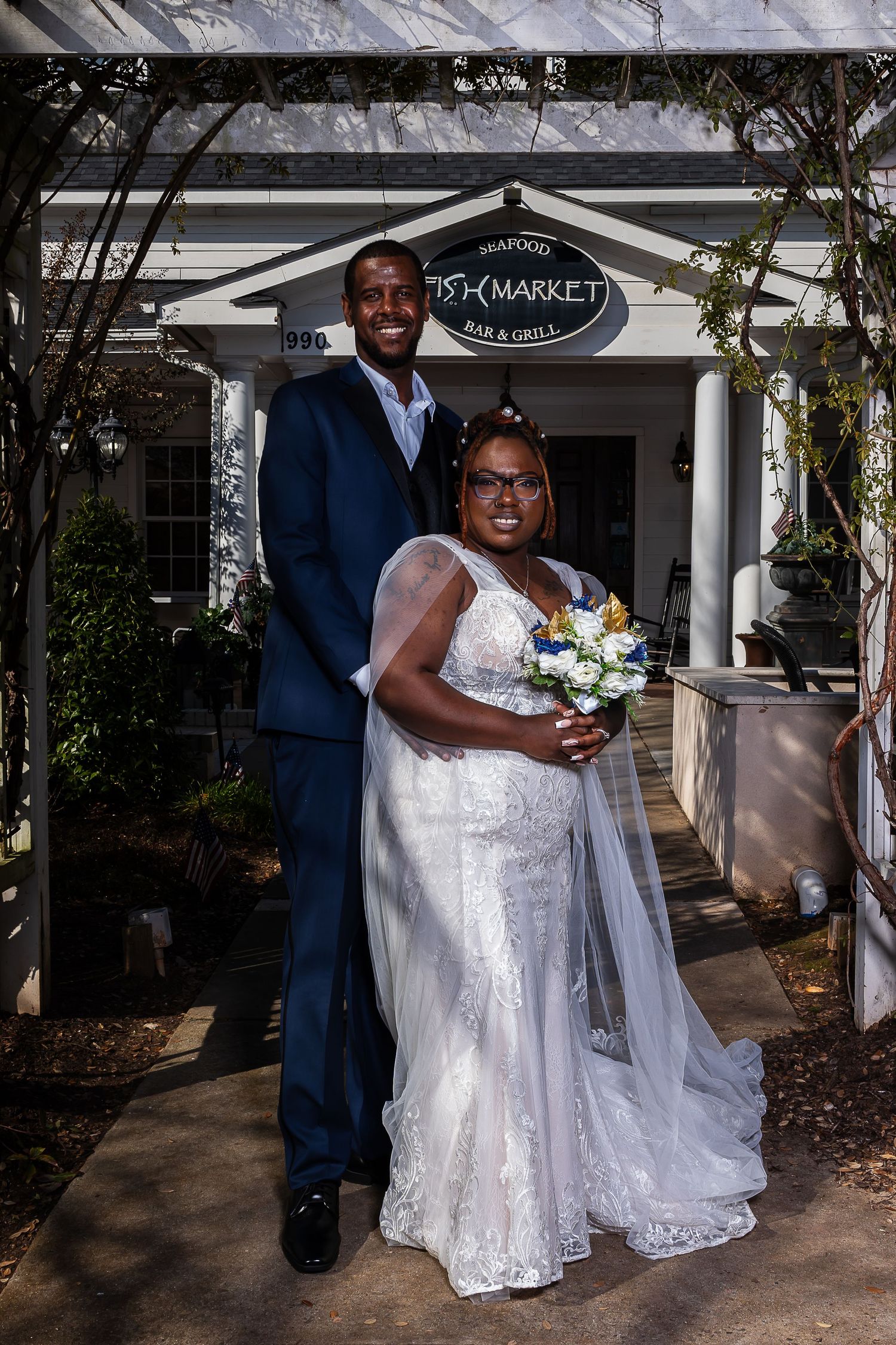 Bride and groom posing together outside Fish Market Seafood Bar and Grill restaurant on their wedding day.