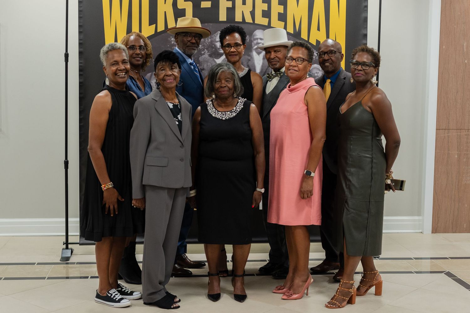 Large group of ten people posing together in front of a Wilks-Freeman event backdrop.