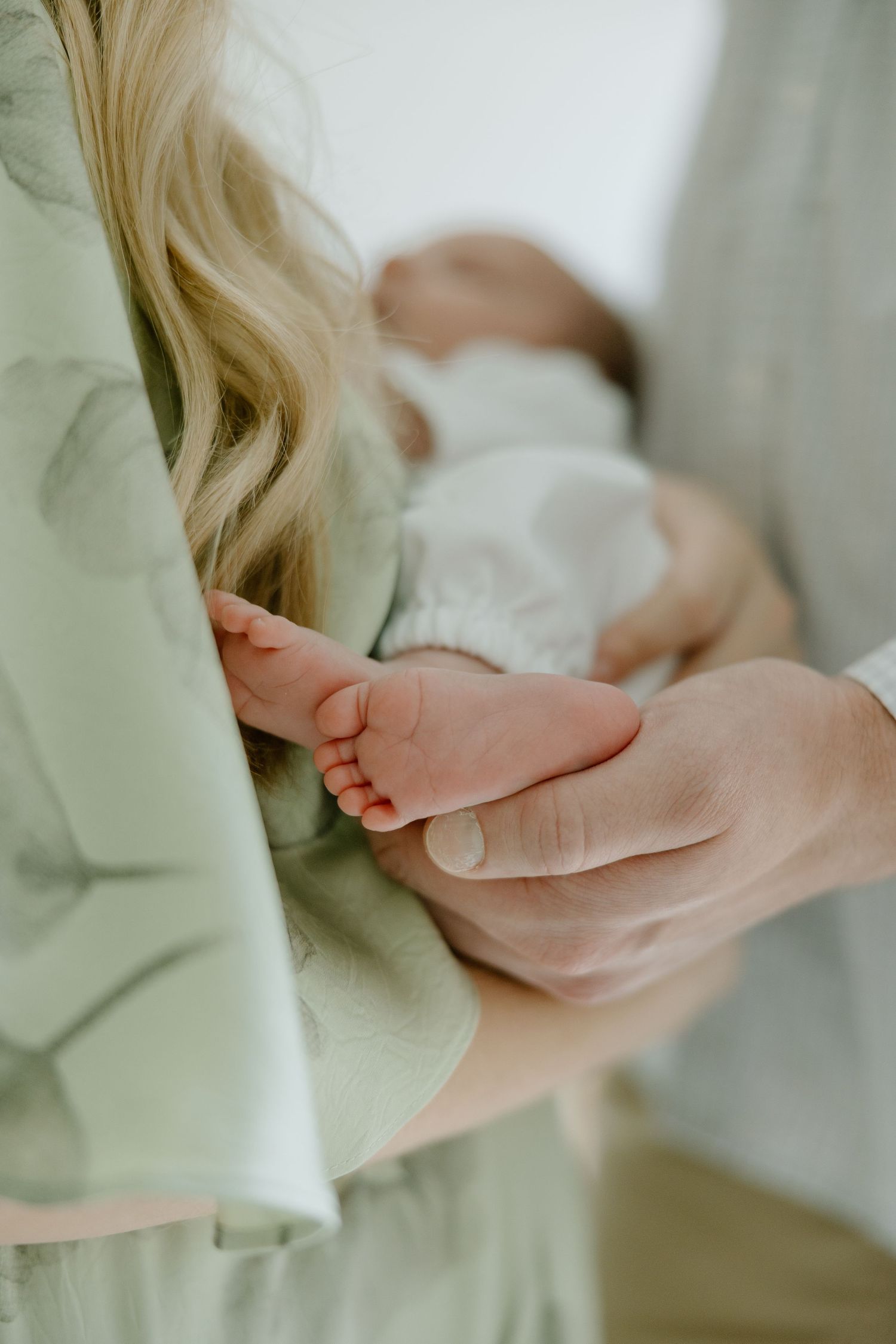 Close-up of parent tenderly holding newborn baby tiny feet in soft natural light.