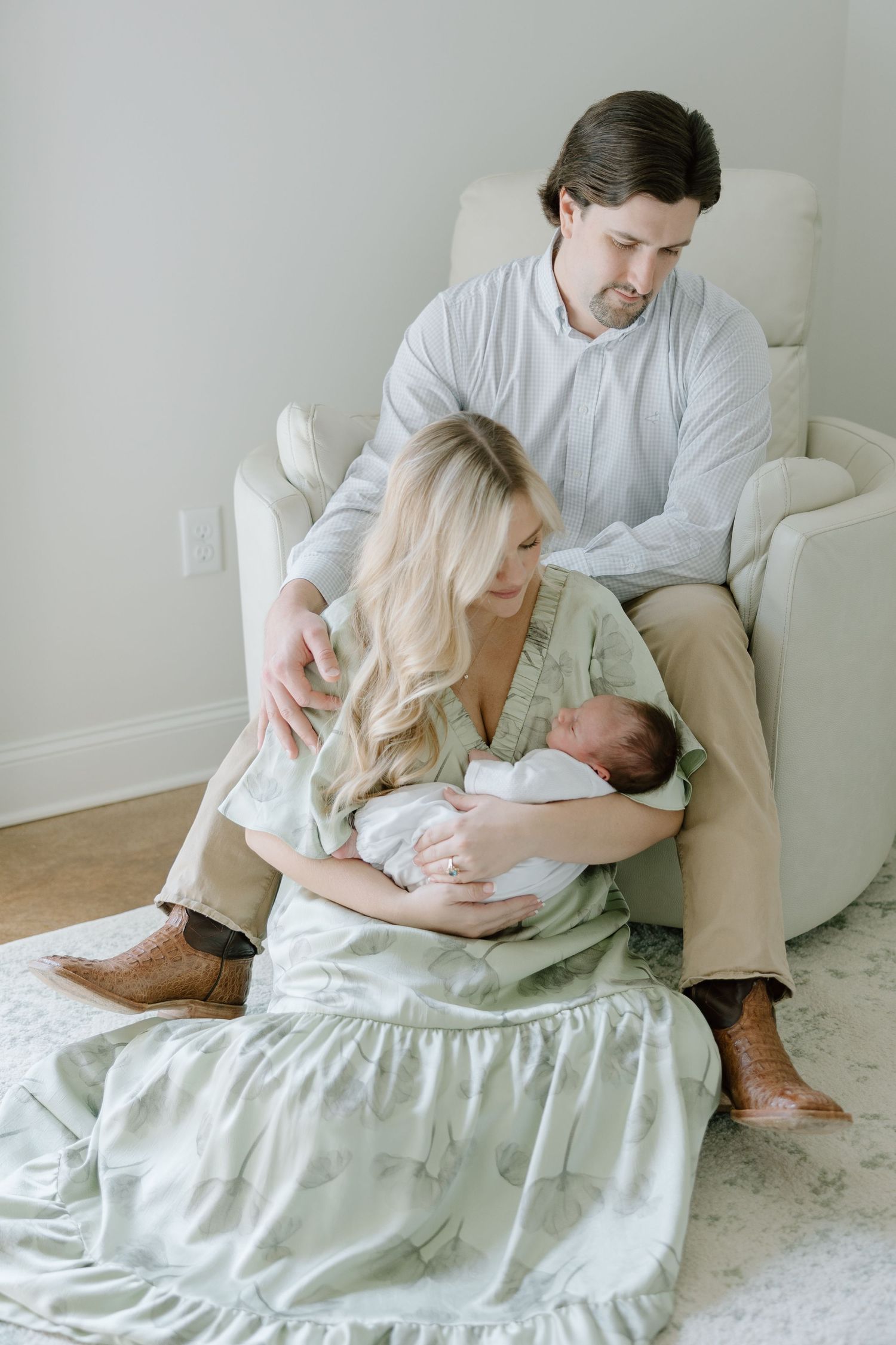 New parents gazing lovingly at their newborn baby in a bright, serene nursery setting.