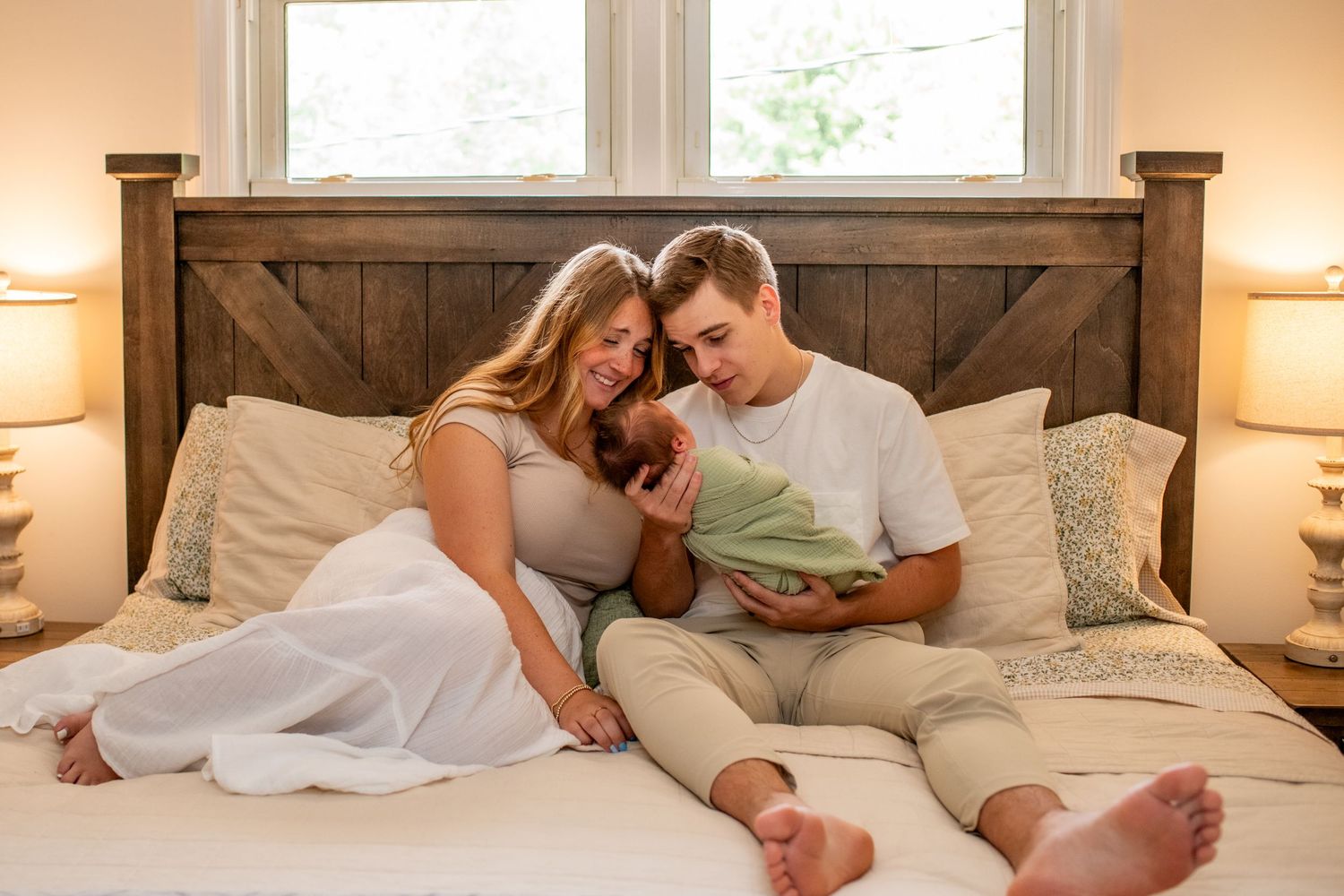 A family relaxes together on a cozy bed while bonding with their newborn.