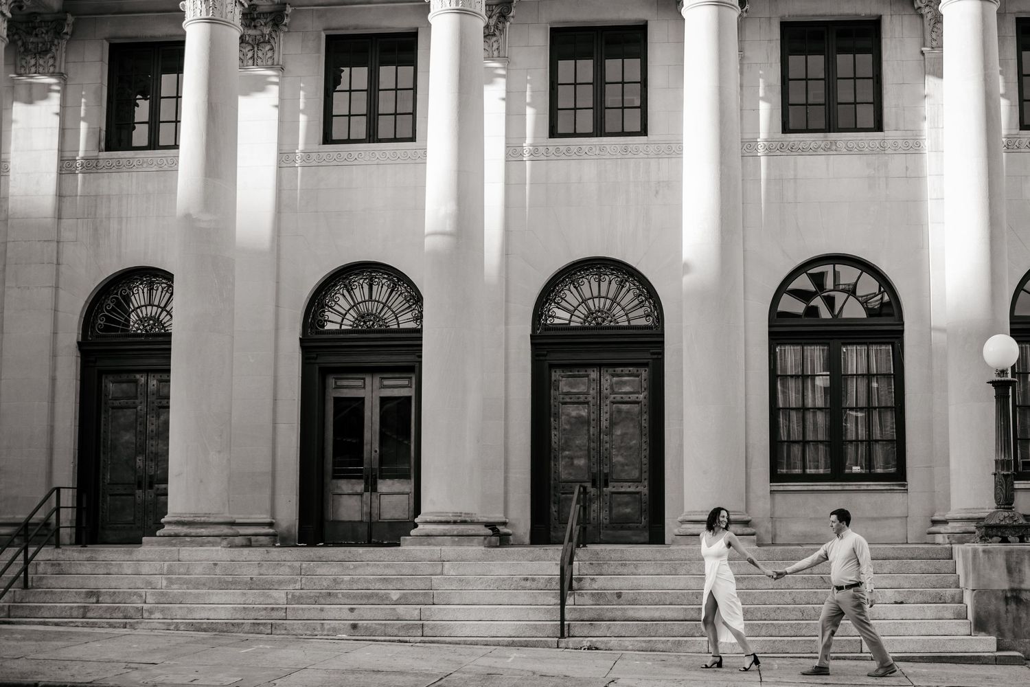 Long architectural view of a historic building with white columns and arched windows.