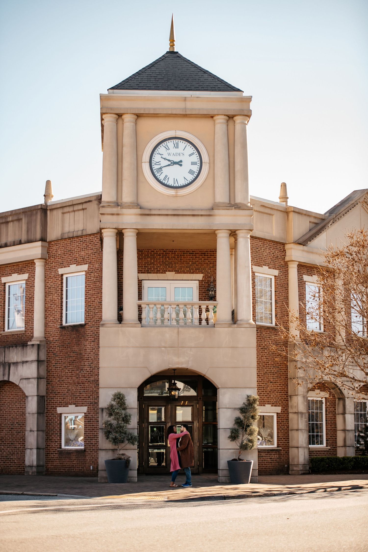 A classic brick building with a prominent clock tower and columns at the entrance.