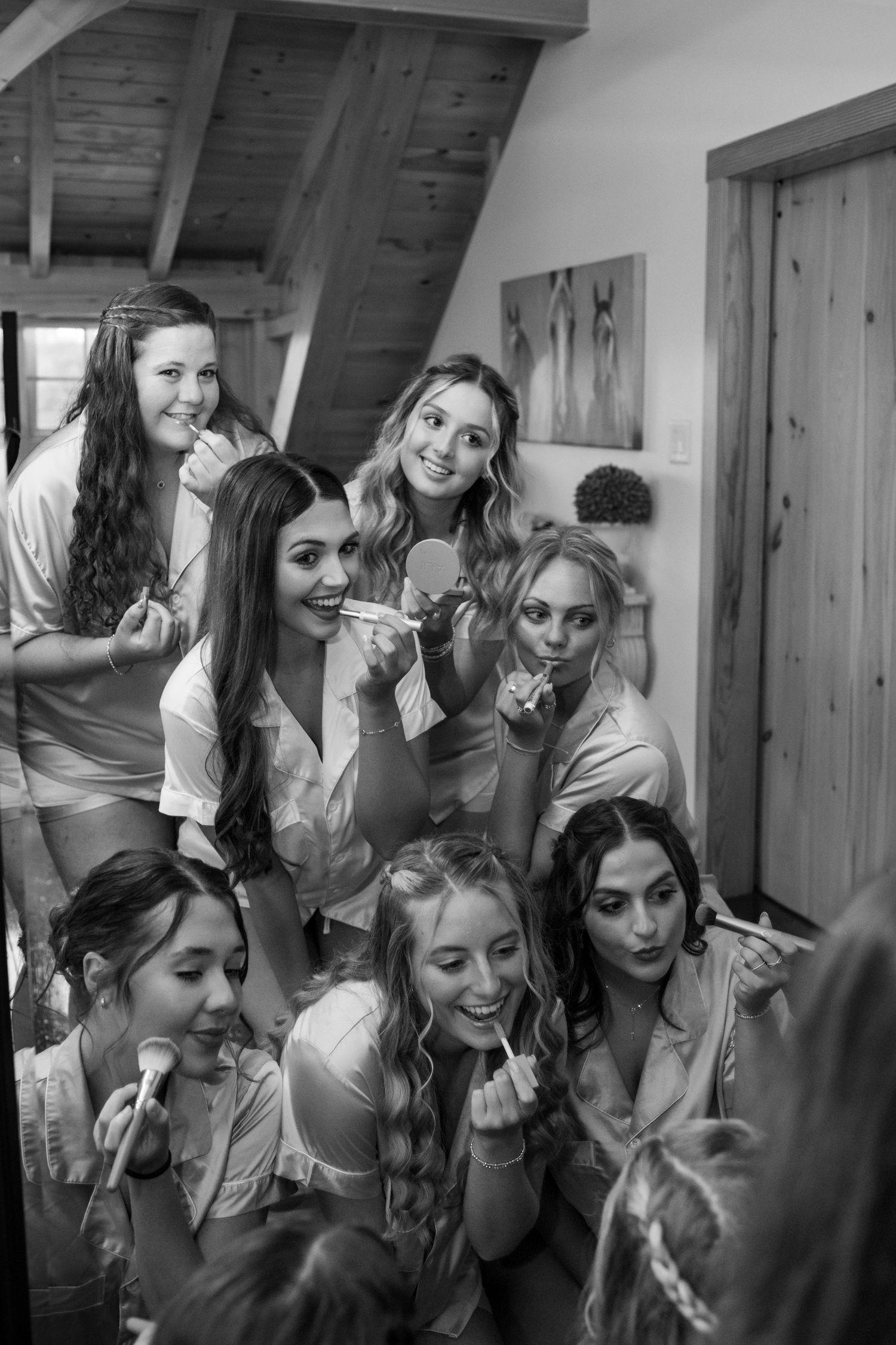 A group of bridesmaids gather together for a candid black and white photo moment.