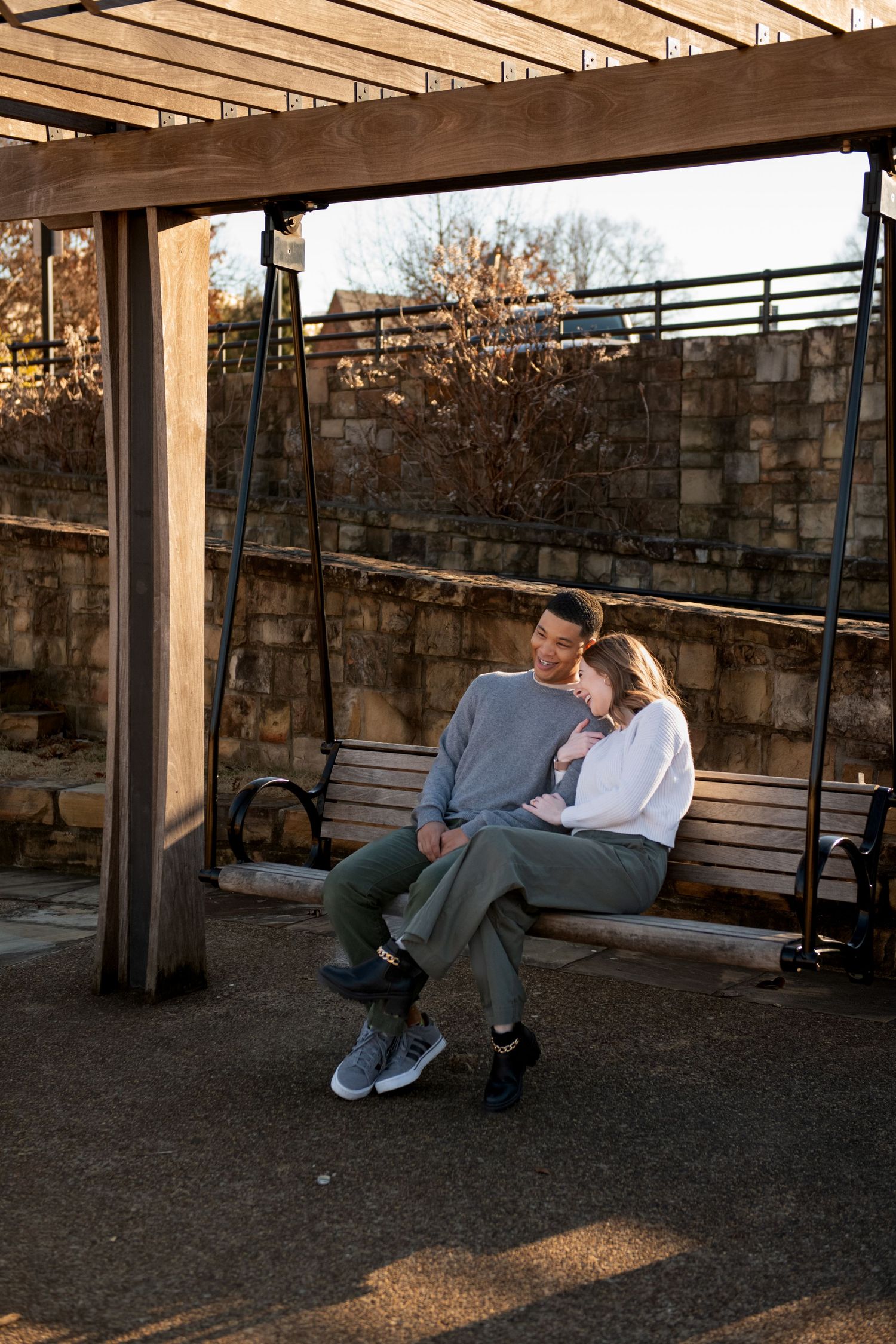 A couple shares an intimate moment while sitting on a wooden porch swing at sunset.