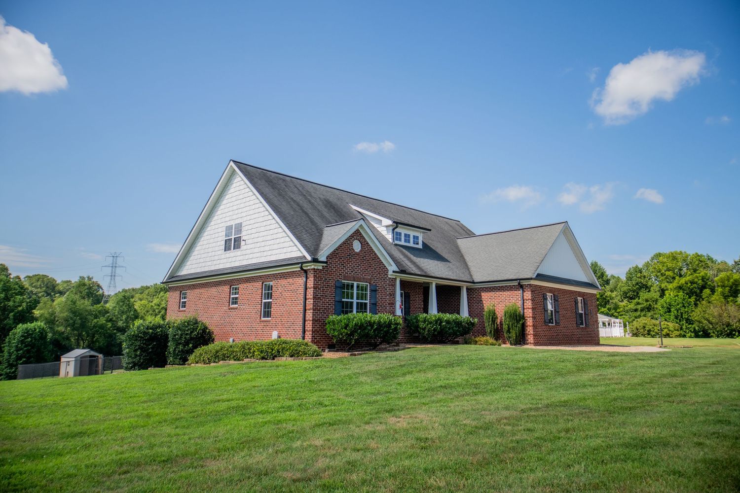 Panoramic view of brick homes situated on rolling green hills with mature landscaping.