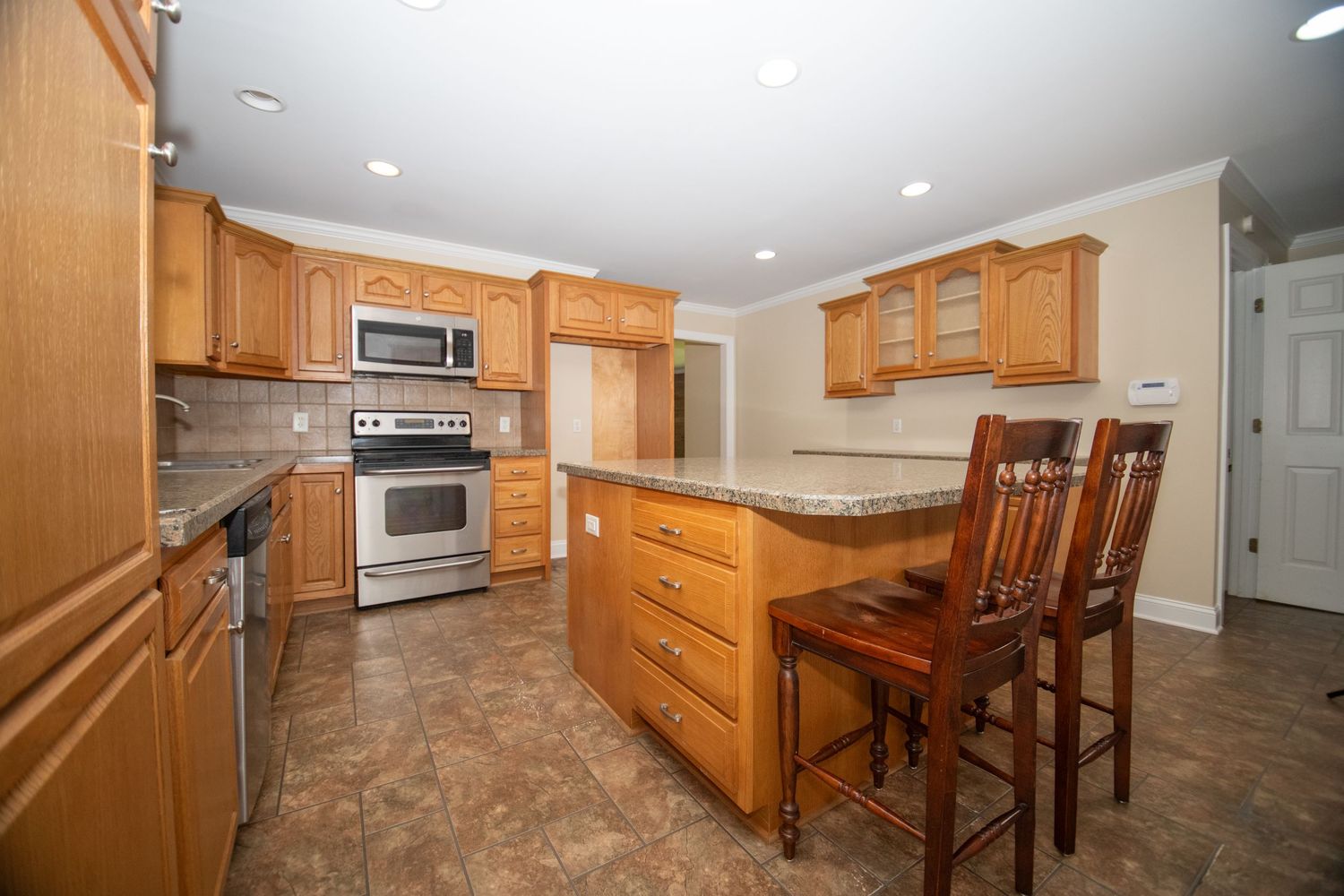 Modern kitchen interior with wooden cabinets and tile flooring.