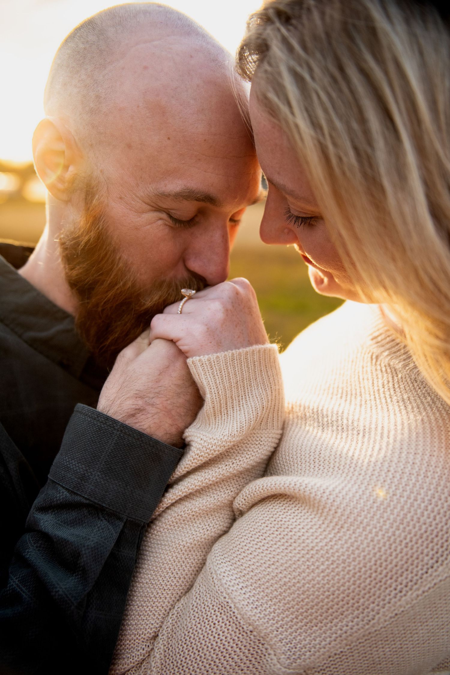 Intimate couple sharing a tender moment in warm sunset light while wearing cozy sweaters.