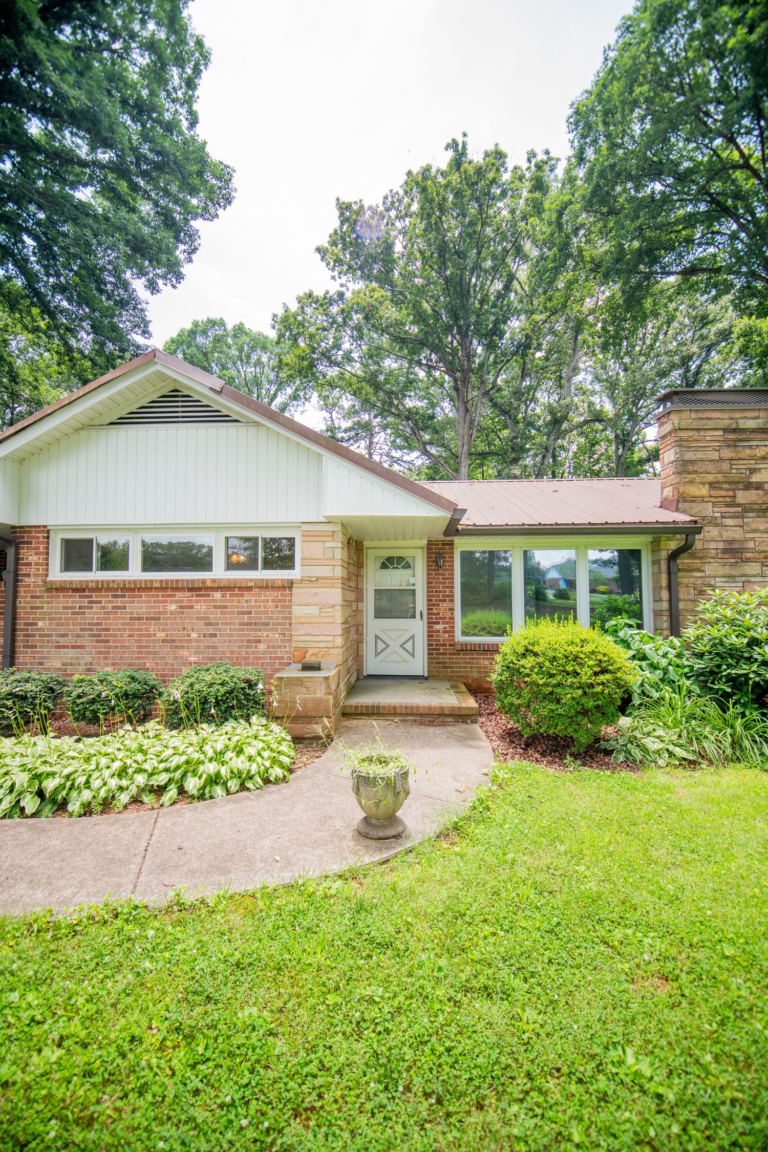 Ranch-style brick house with landscaped front yard and carport.