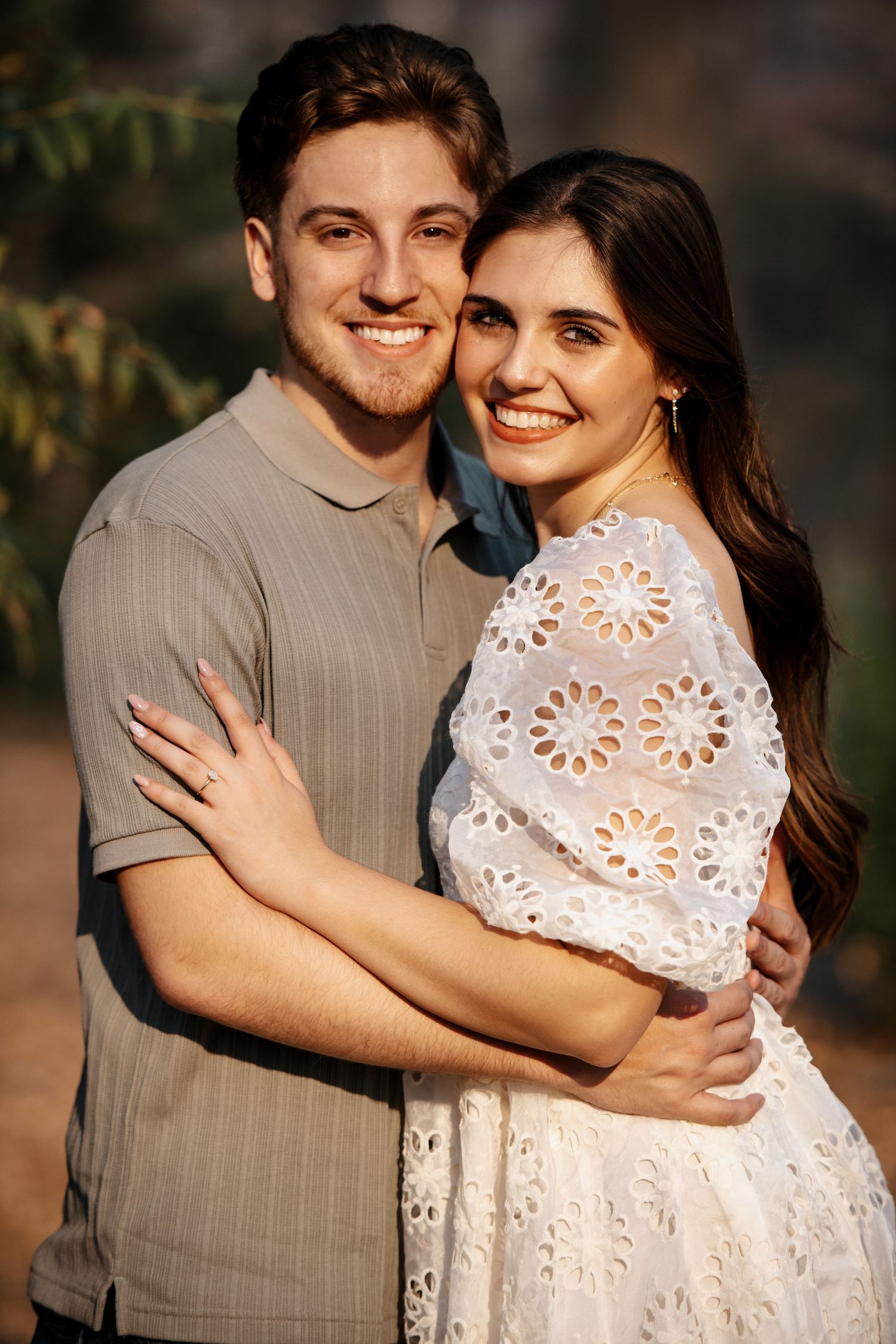 Couple in white and grey outfits sharing affectionate embraces outdoors.