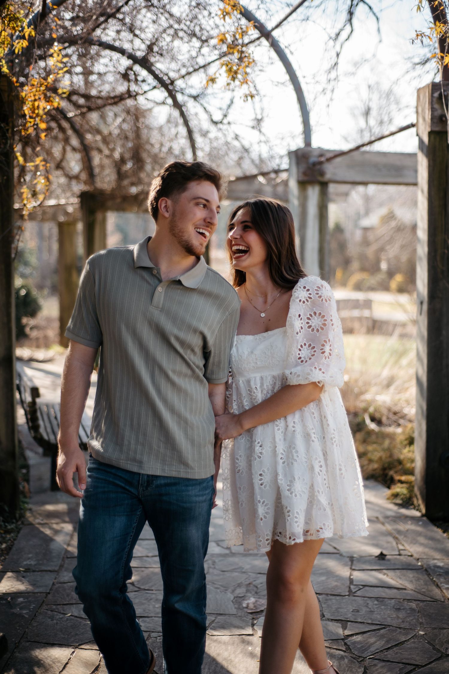 A couple shares joyful moments while walking along a stone path outdoors.