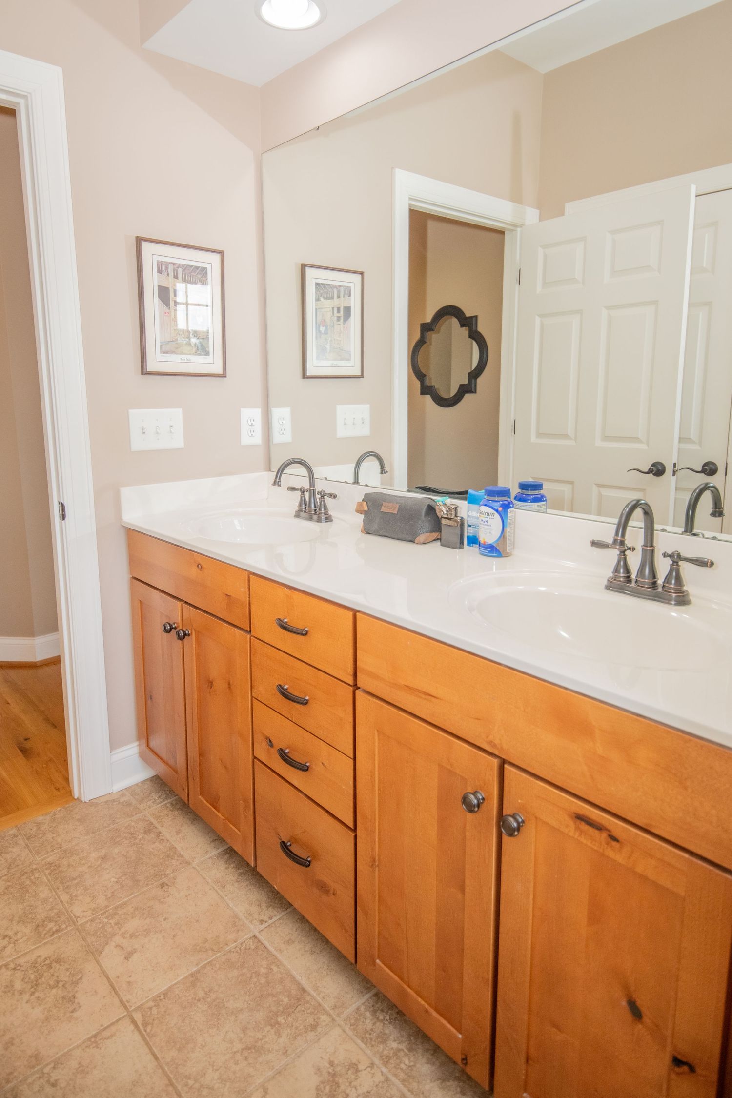 Modern bathroom featuring honey-colored cabinets and white countertops with dual sinks.